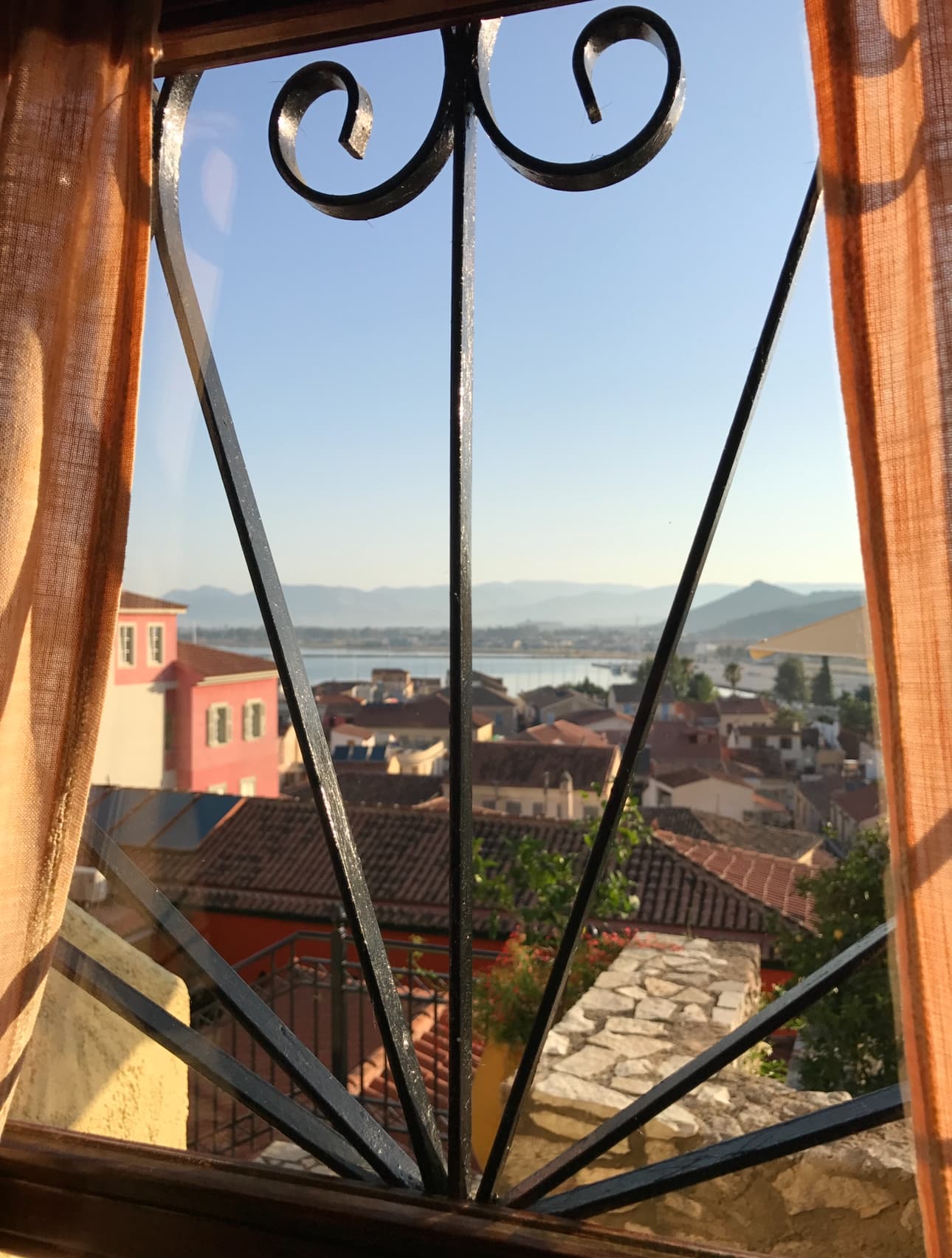 A view of the water from a hotel window overlooking tiled rooftops.
