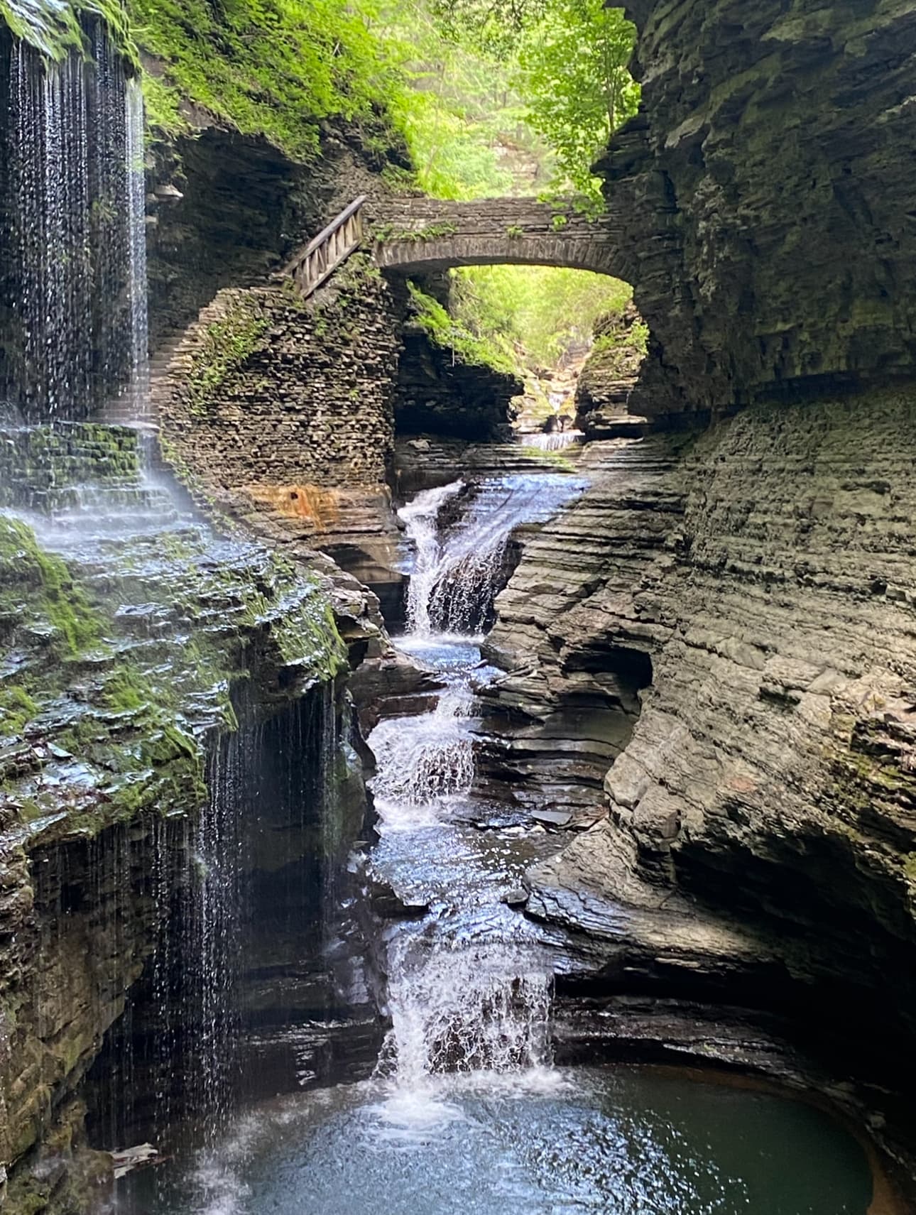 Waterfalls cascade down rocky ledges on a sunny day.