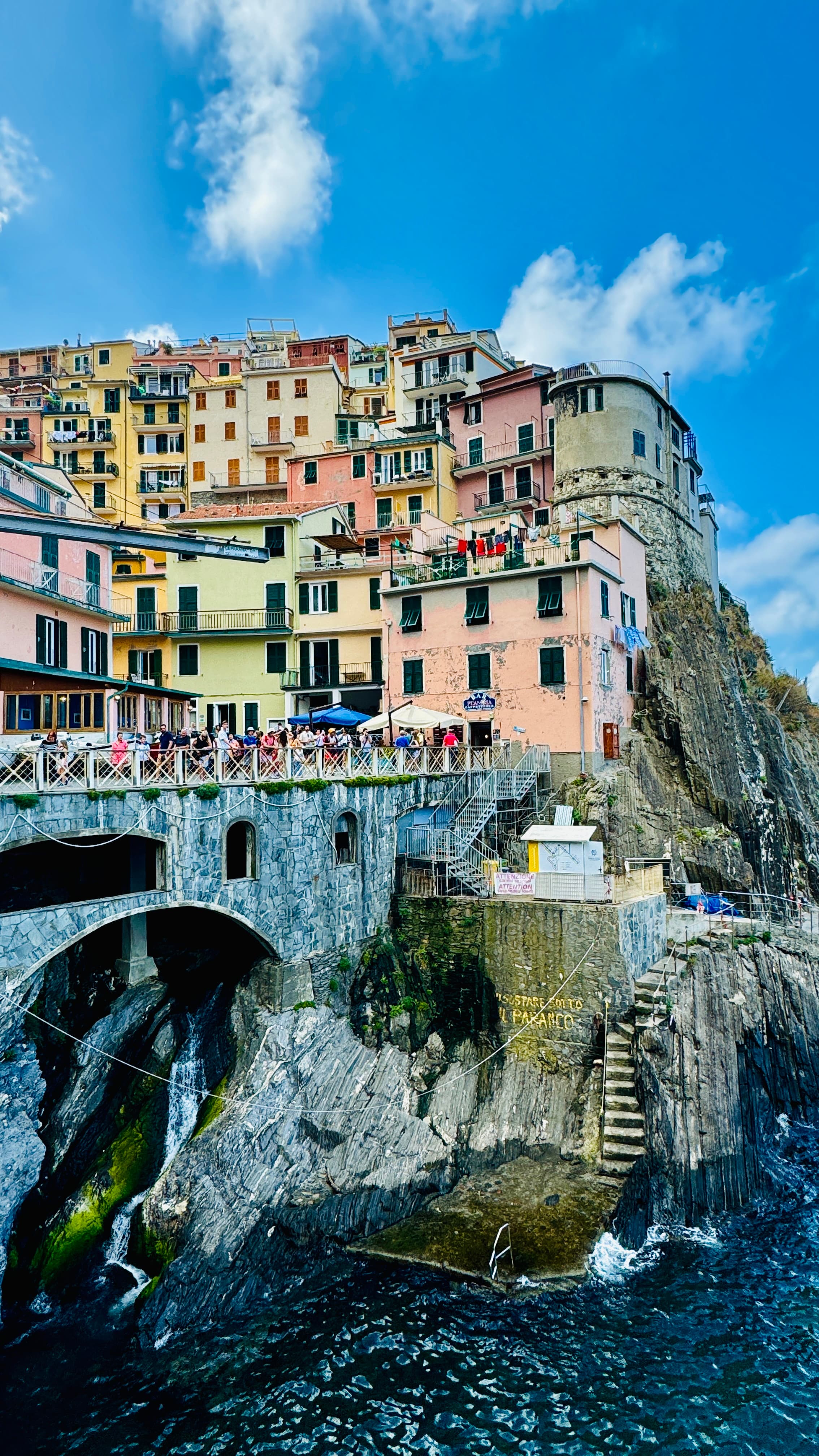 View of colorful buildings atop a bridge with water underneath during the daytime.