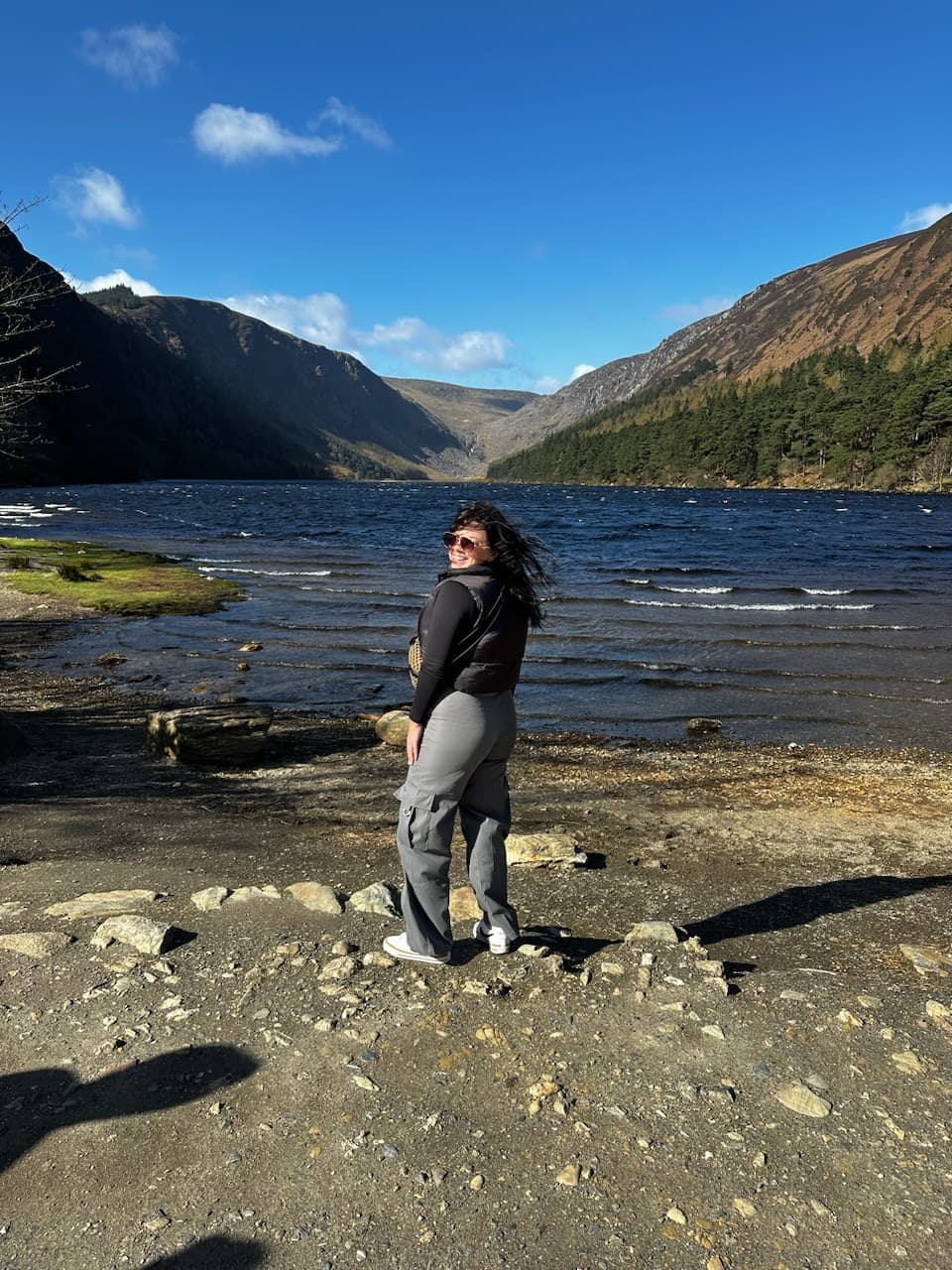 Advisor posing near a lake as waves lap the shore on a sunny day. 