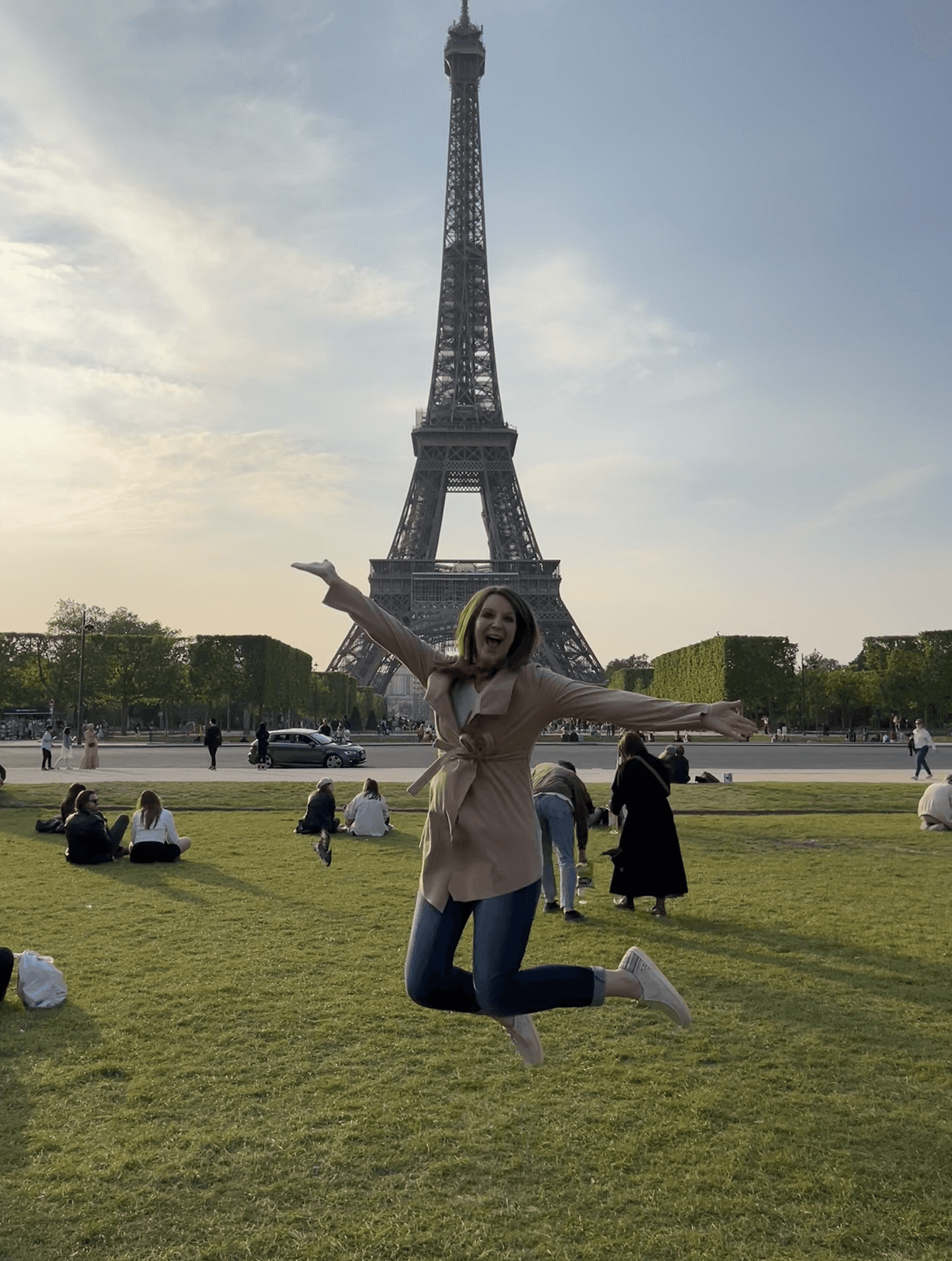 Advisor posing on a grassy field with the Eiffel Tower in the distance. 