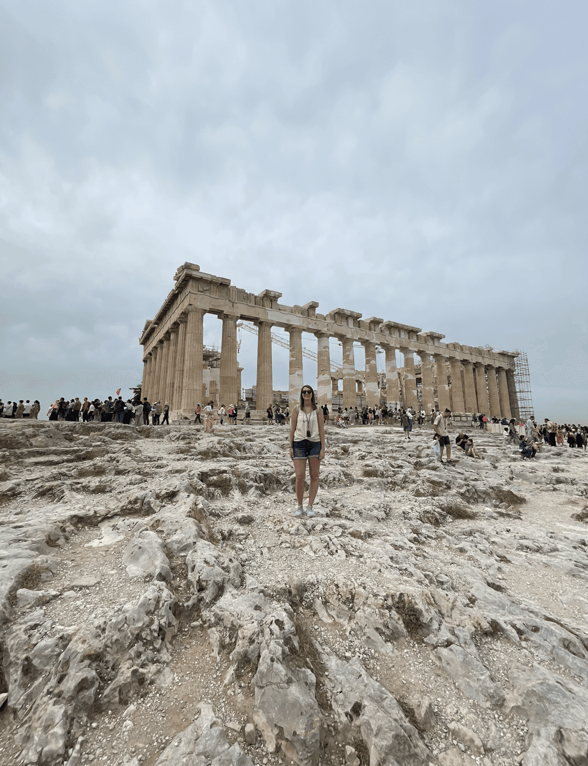 Advisor posing for an image with ruins in the distance during the daytime. 
