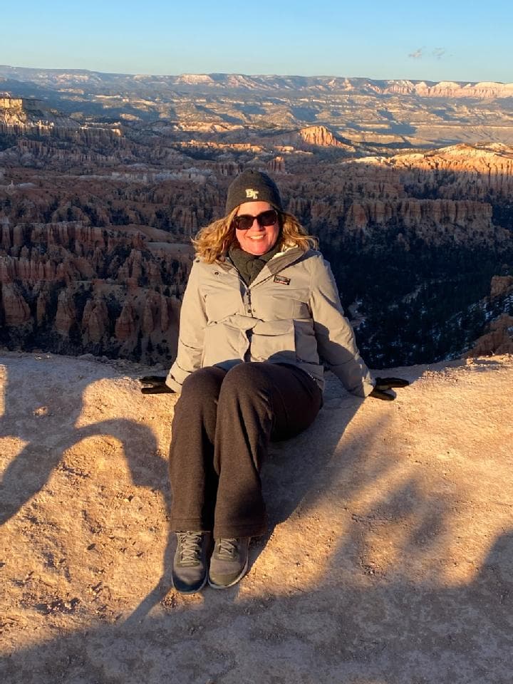 A person sitting on a hillside smiling for a photograph during the daytime