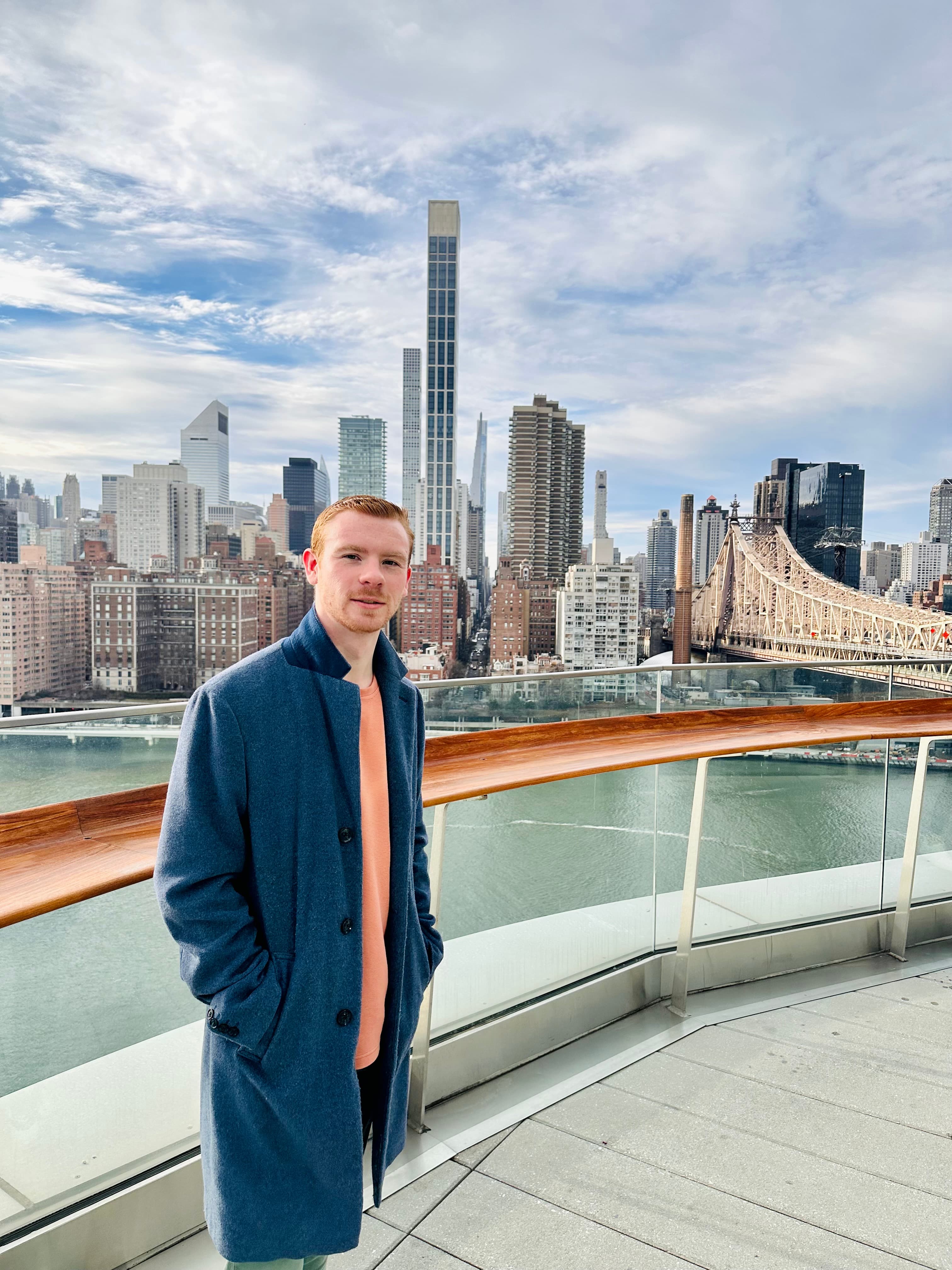 Advisor posing on a boat with a city in the distance. 