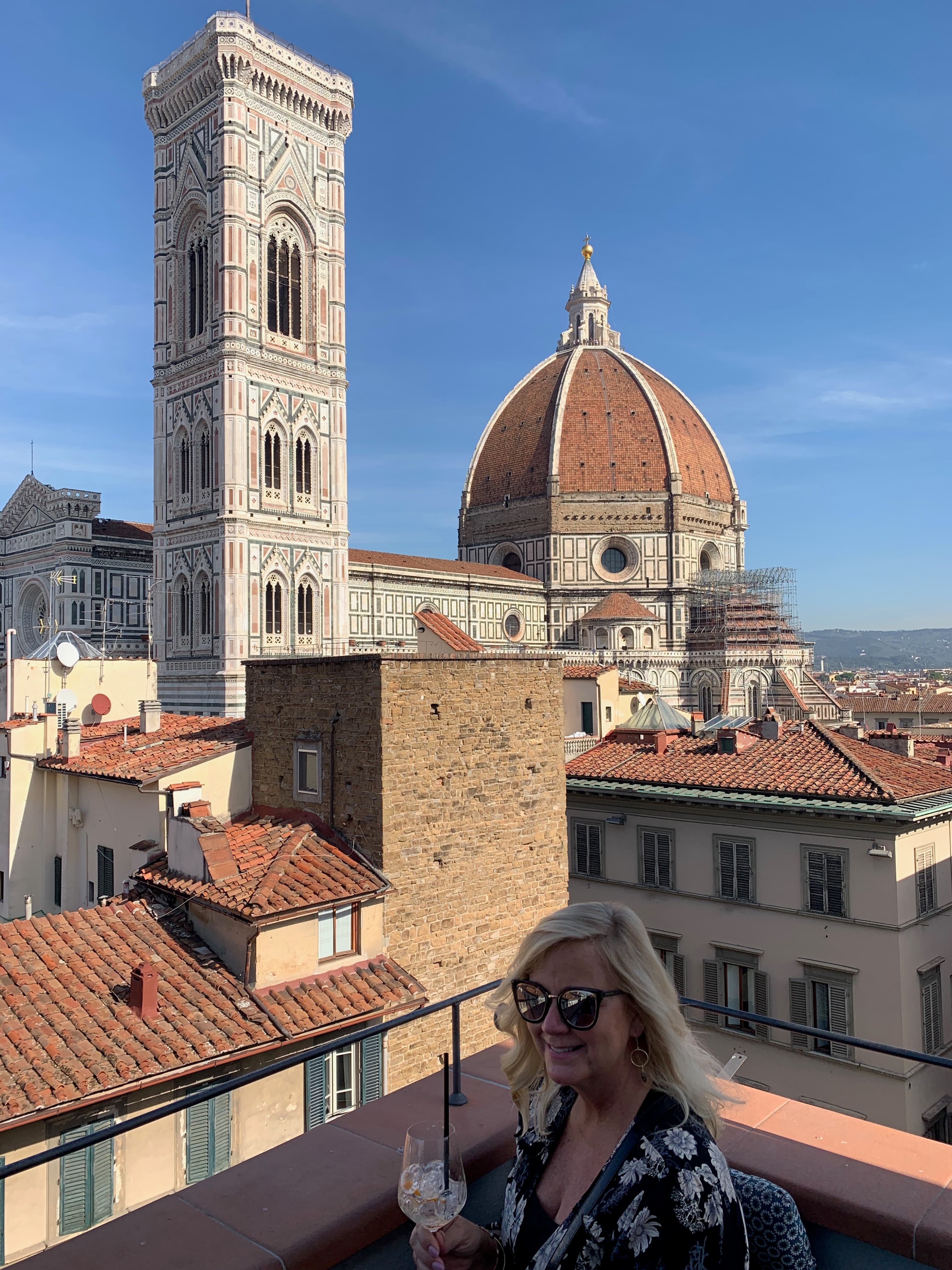 A view of advisor with a cocktail and a city in the distance at dusk. 