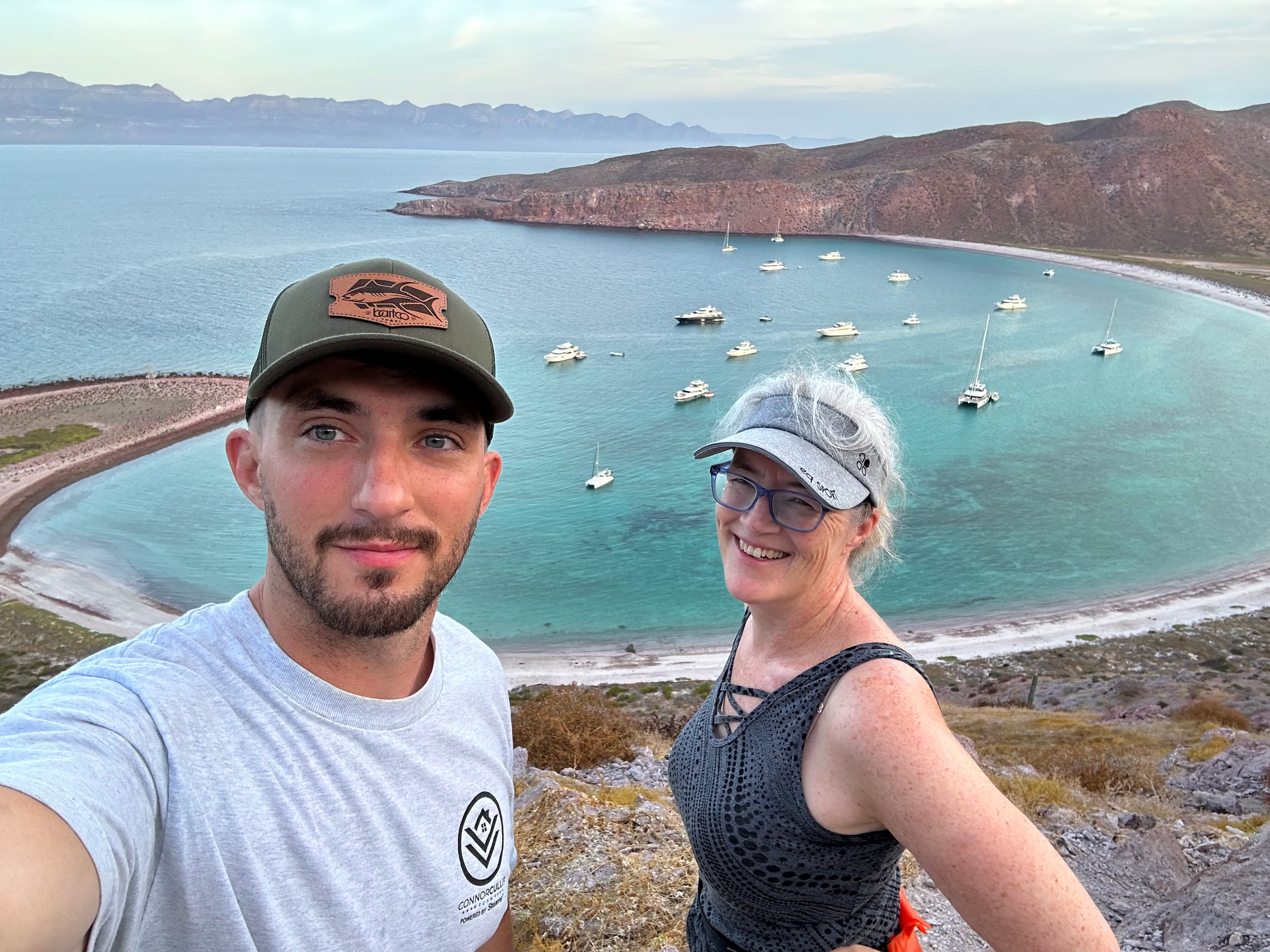 Advisor and son taking a selfie on a hike overlooking a beautiful bay with ships offshore