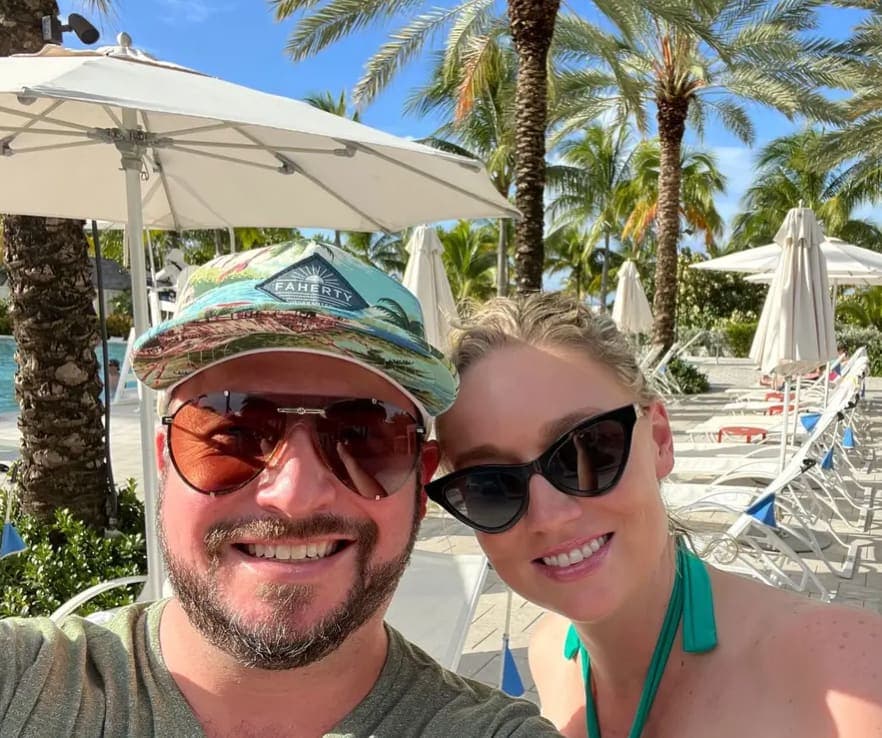 Advisor and partner smiling for a selfie poolside at a resort