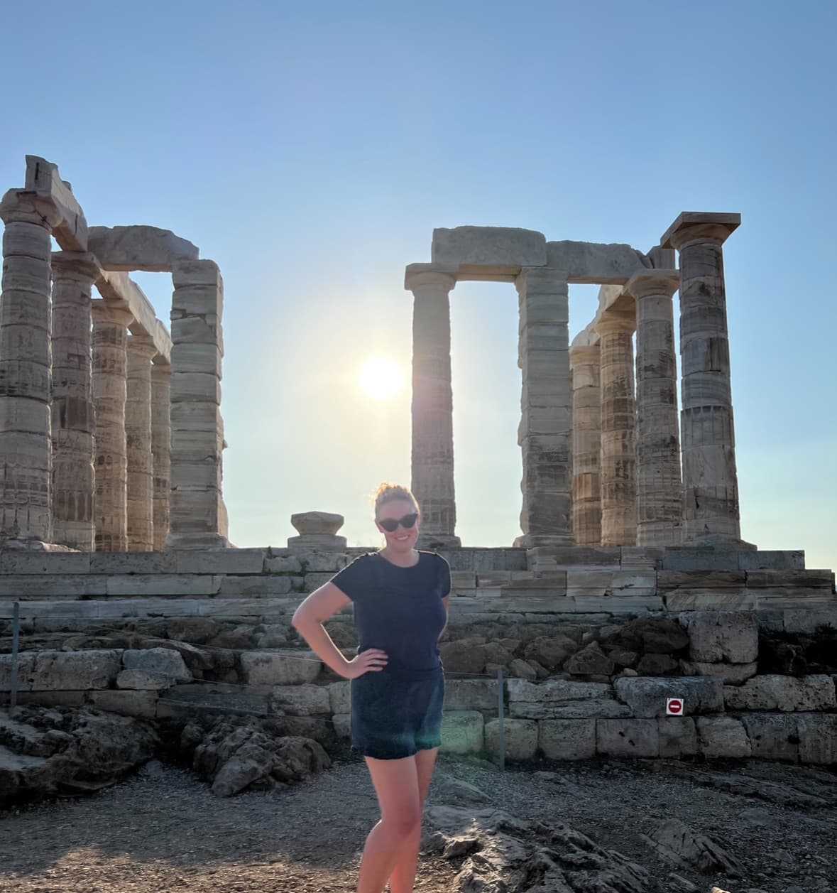 Advisor posing with hands on hips in front of ancient column ruins on a sunny day