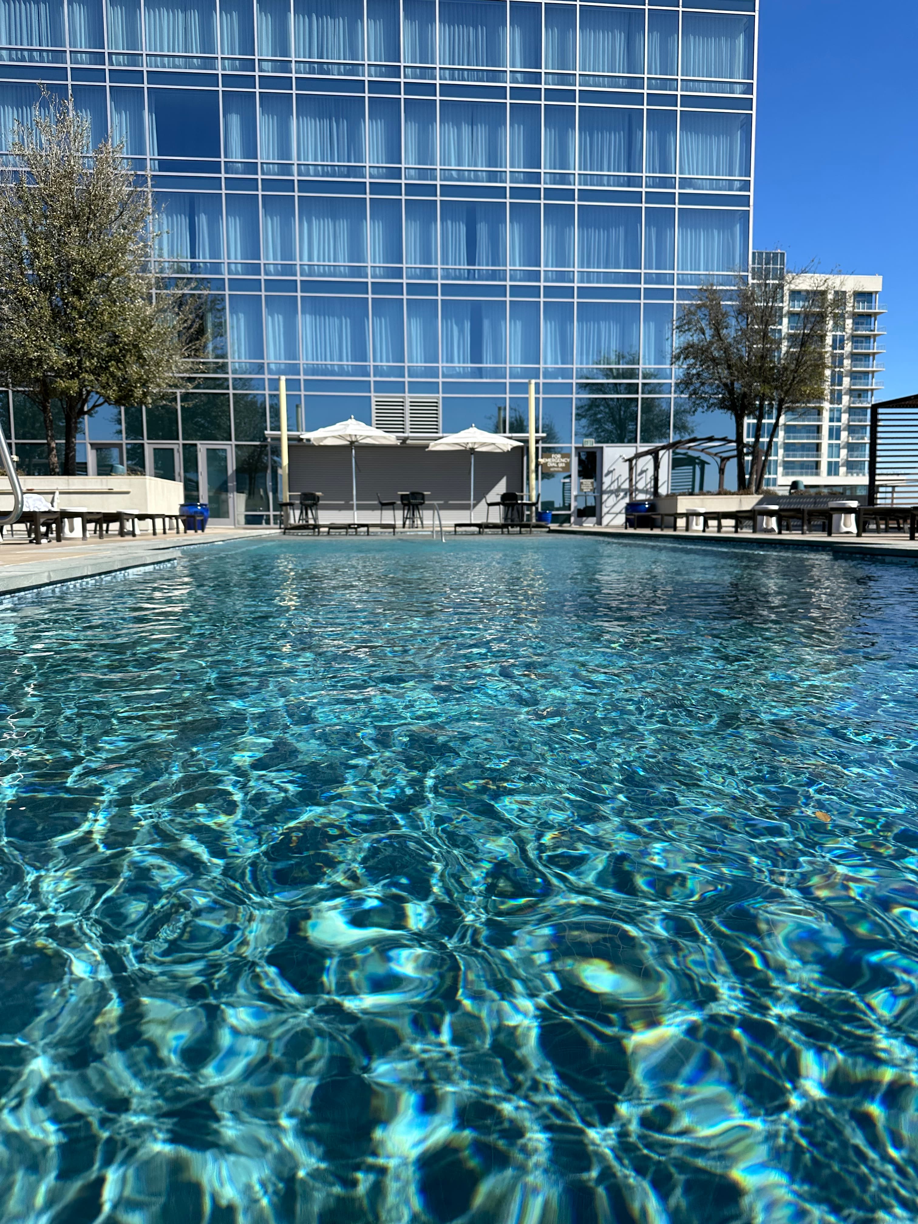 View of an empty resort pool with a glass building in the background