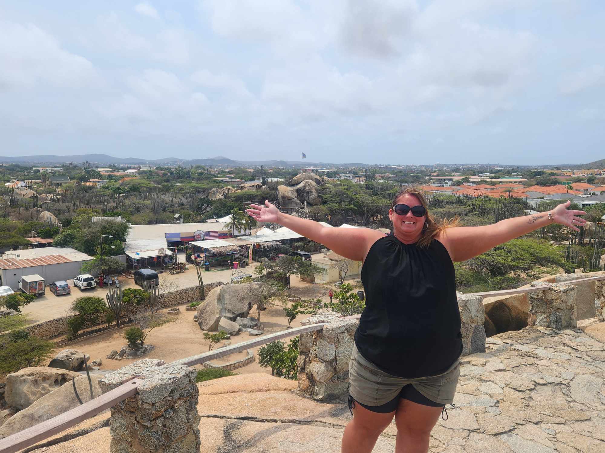 Advisor posing with arms outstretched at a viewpoint on a cloudy day