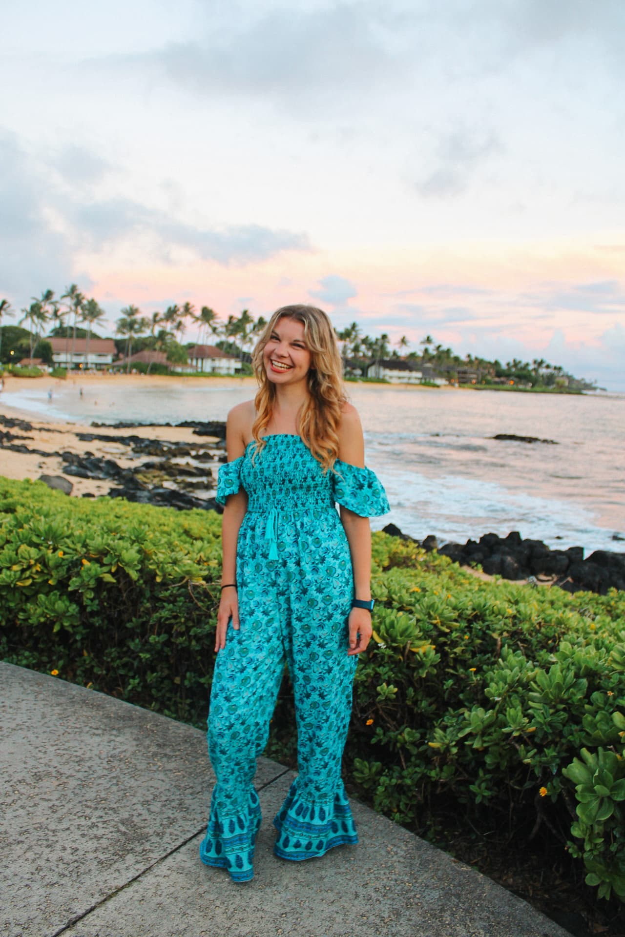 Advisor in a blue jumpsuit smiling by a beautiful beach at sunset