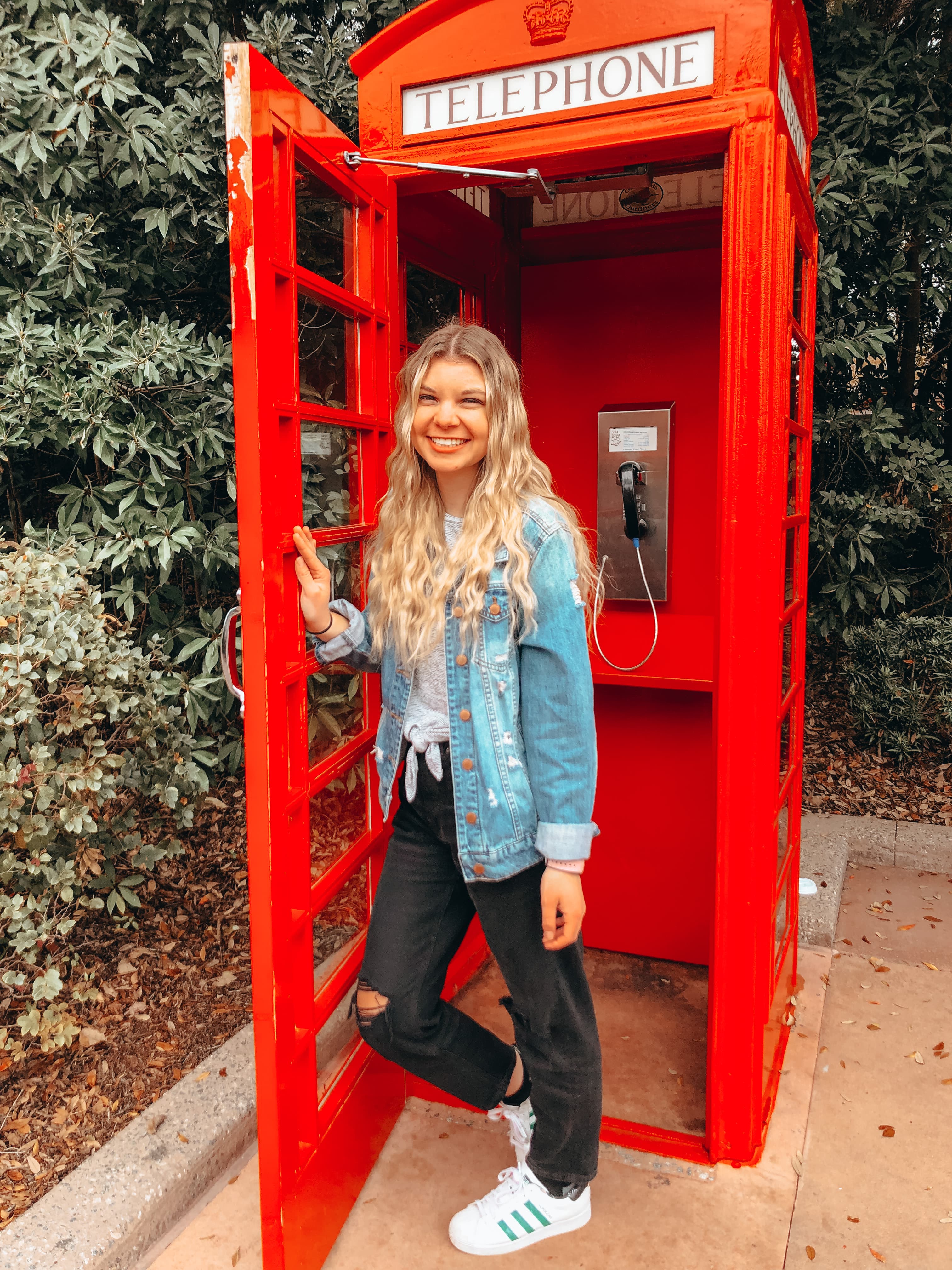Advisor in a denim jacket posing inside a red telephone box