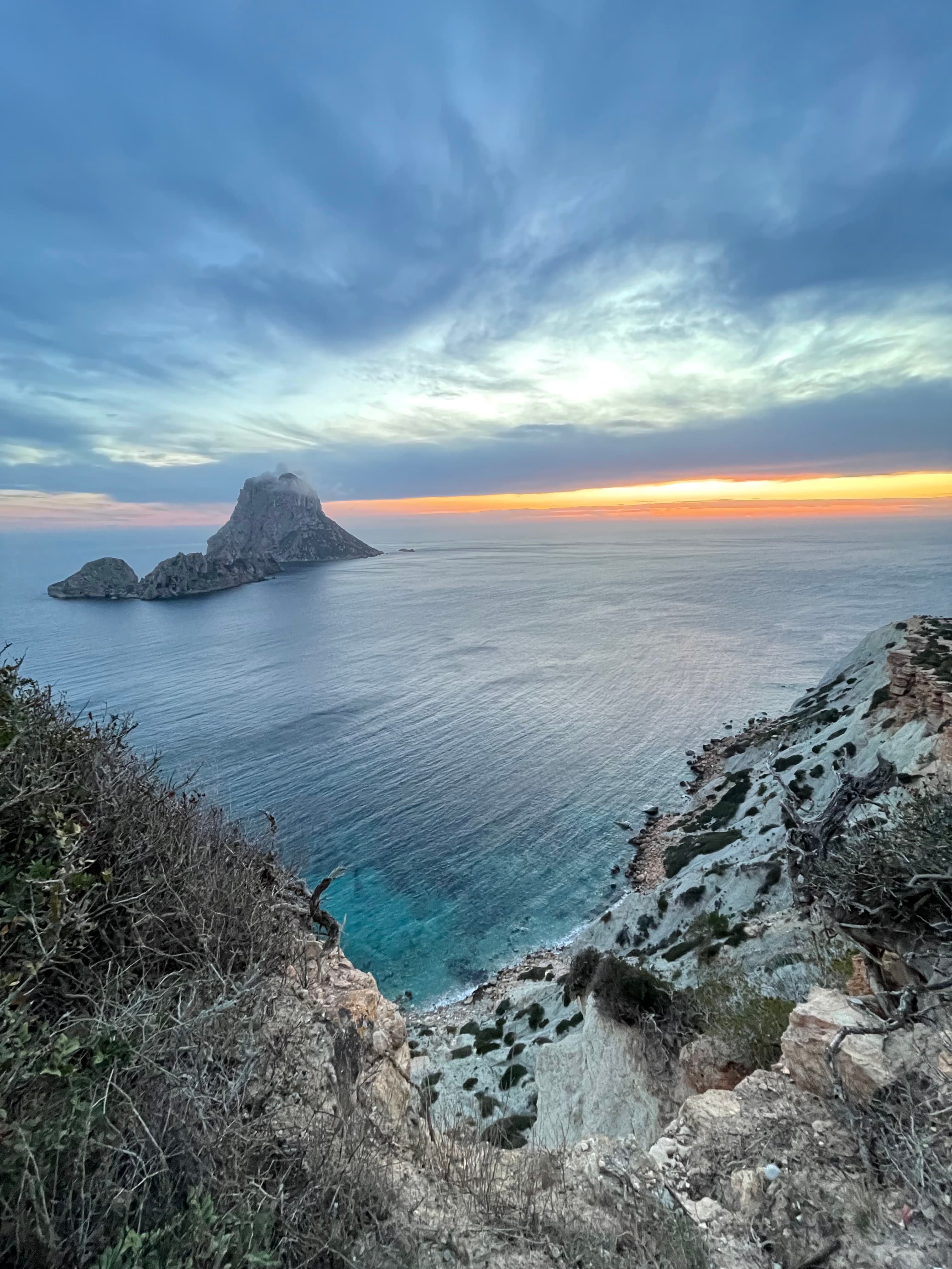 View of the sun setting over the ocean’s horizon seen from a cliff