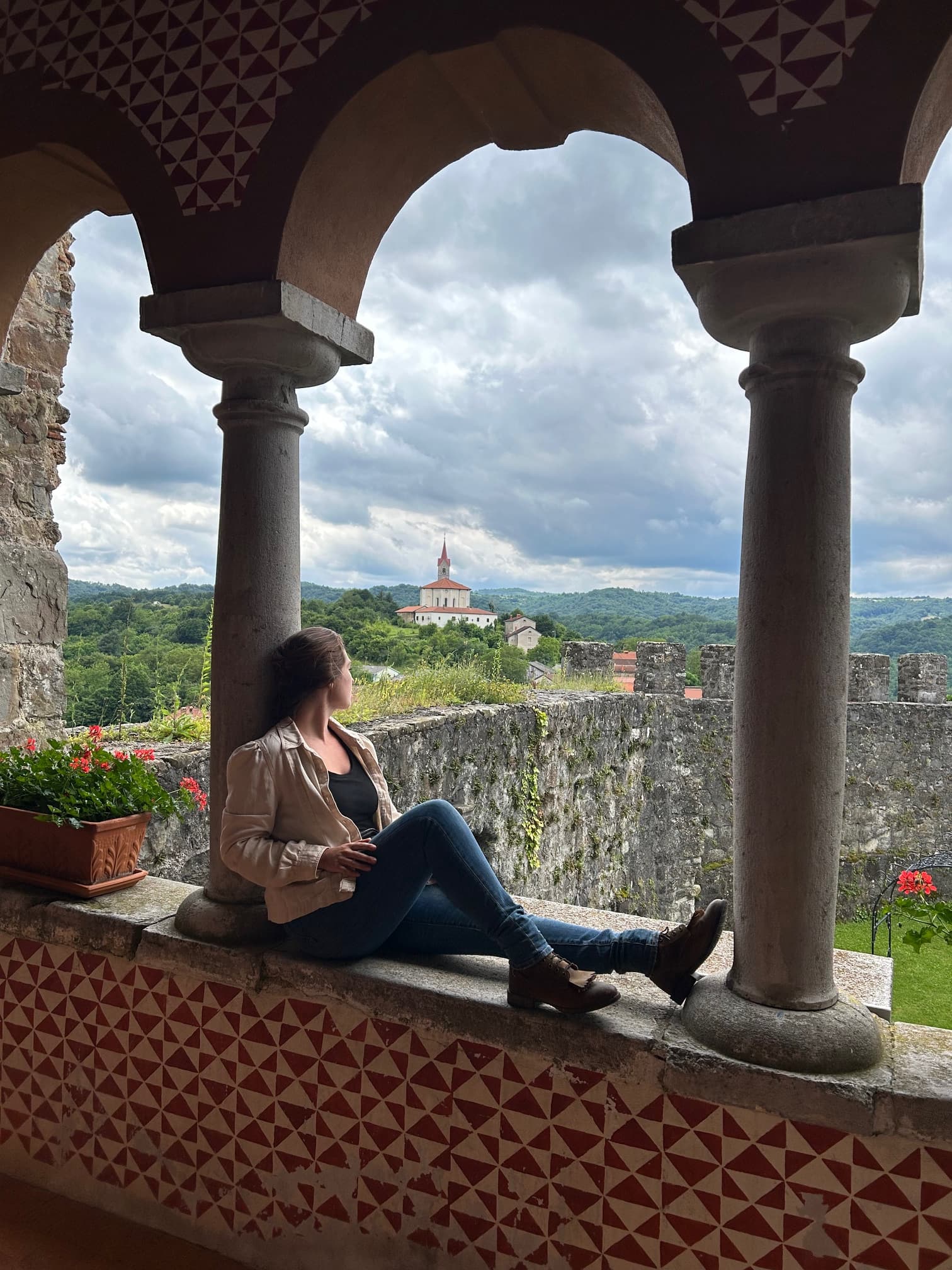 A person sitting on a wall looking out onto a view of a landscape