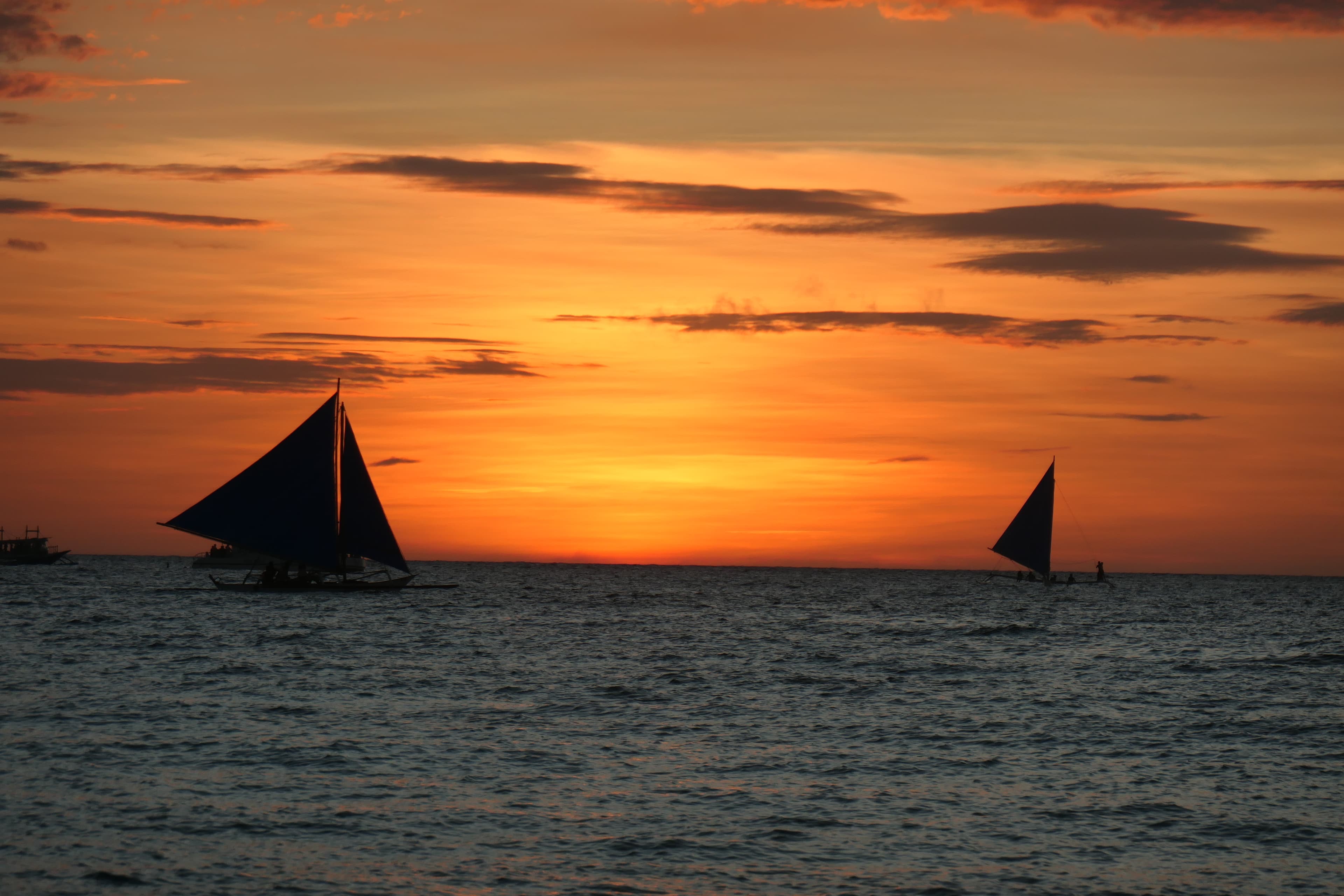 Boats sailing in the water during an orange sunset