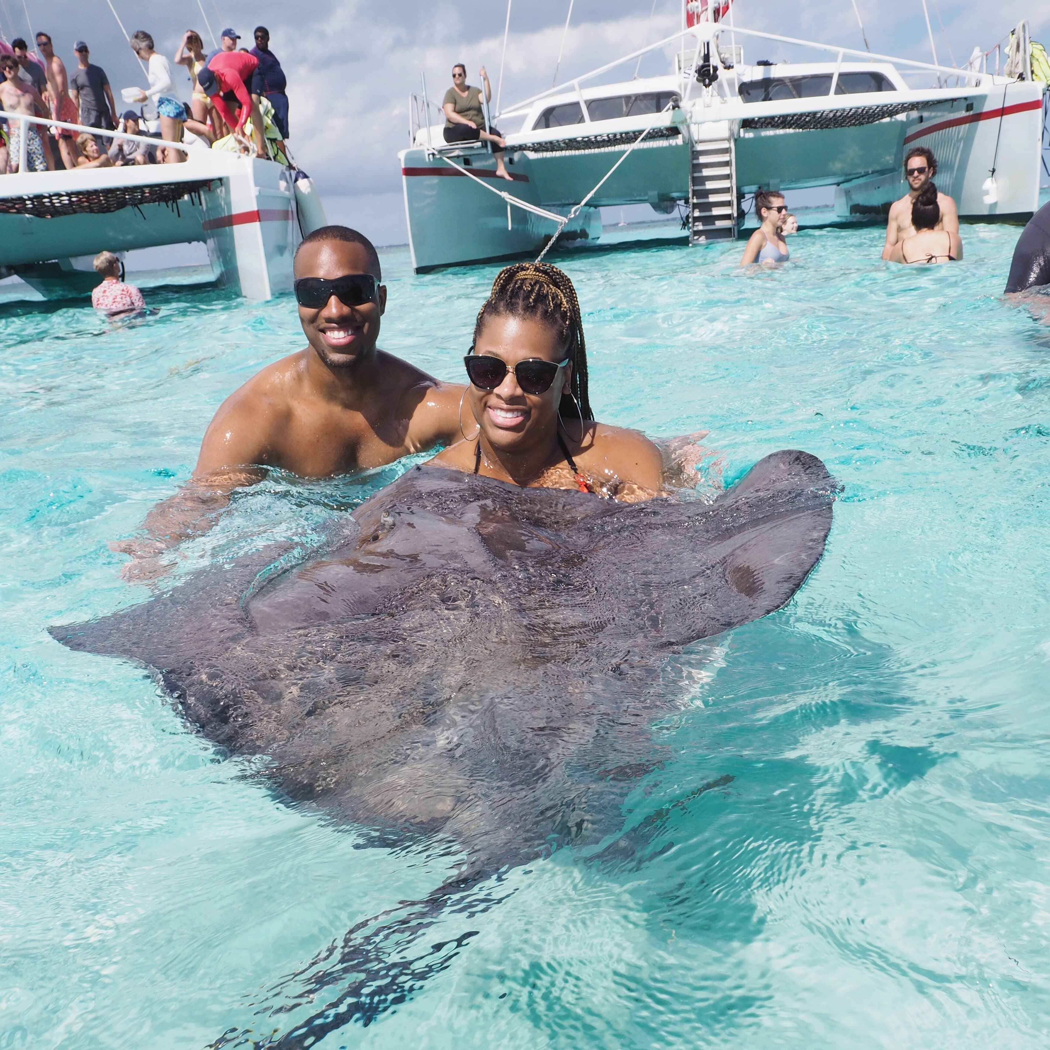 Advisor posing in crystal-clear waters near a sting ray on a sunny afternoon.