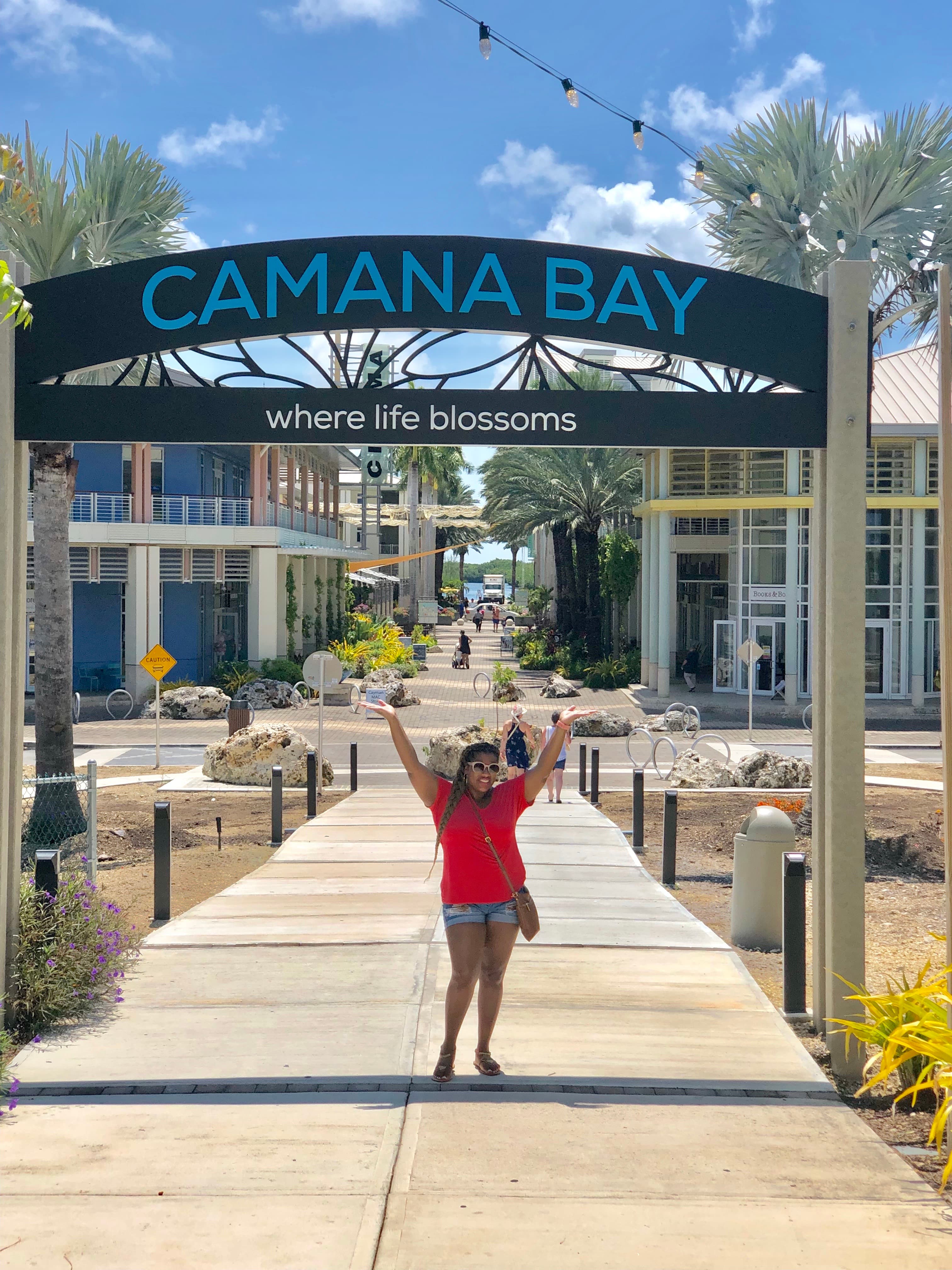 Advisor posing below sign reading, "Camana Bay" on a sunny afternoon.