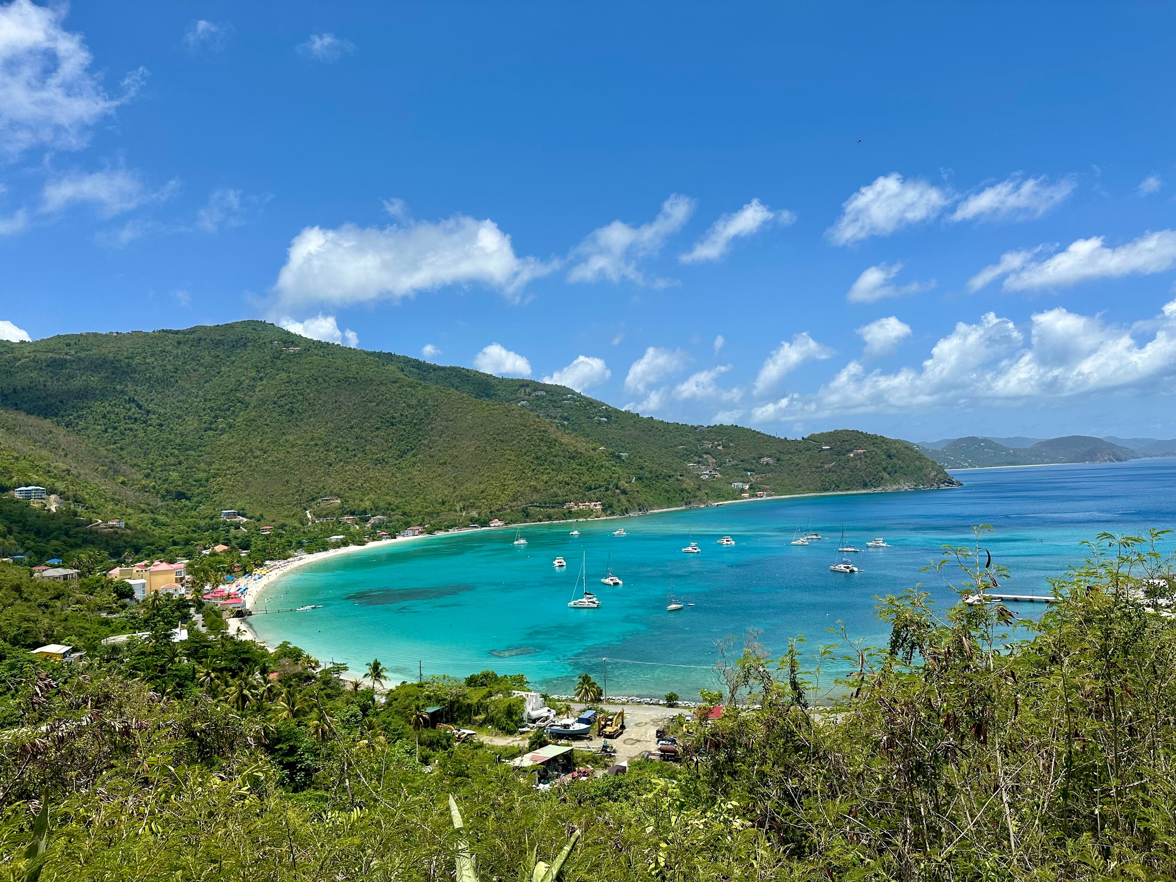 A view of turquoise blue waters and tree covered mountains on a beautiful day. 