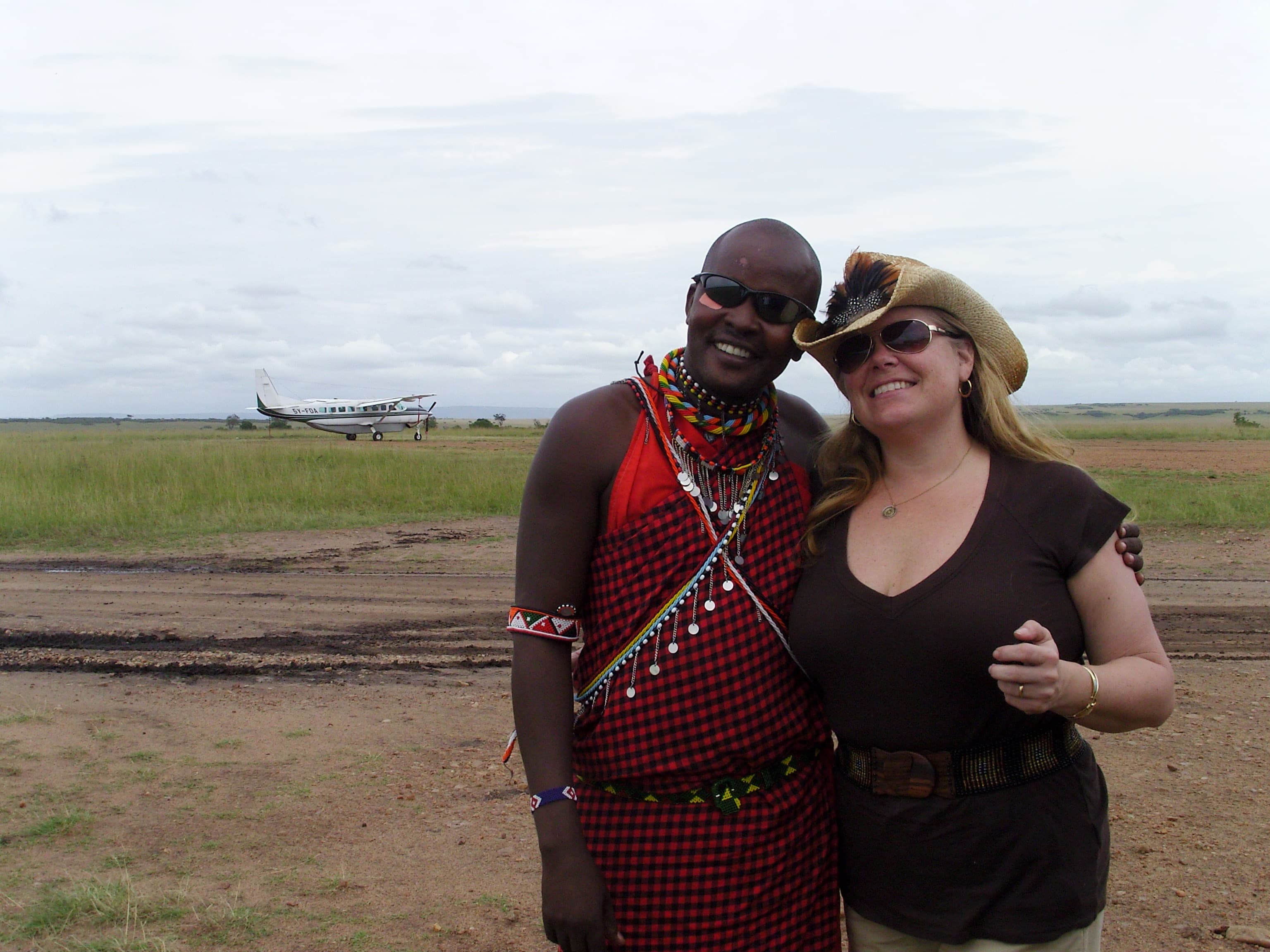 A man and woman dressed in traditional attire stand together, smiling for a photograph in a vibrant setting.