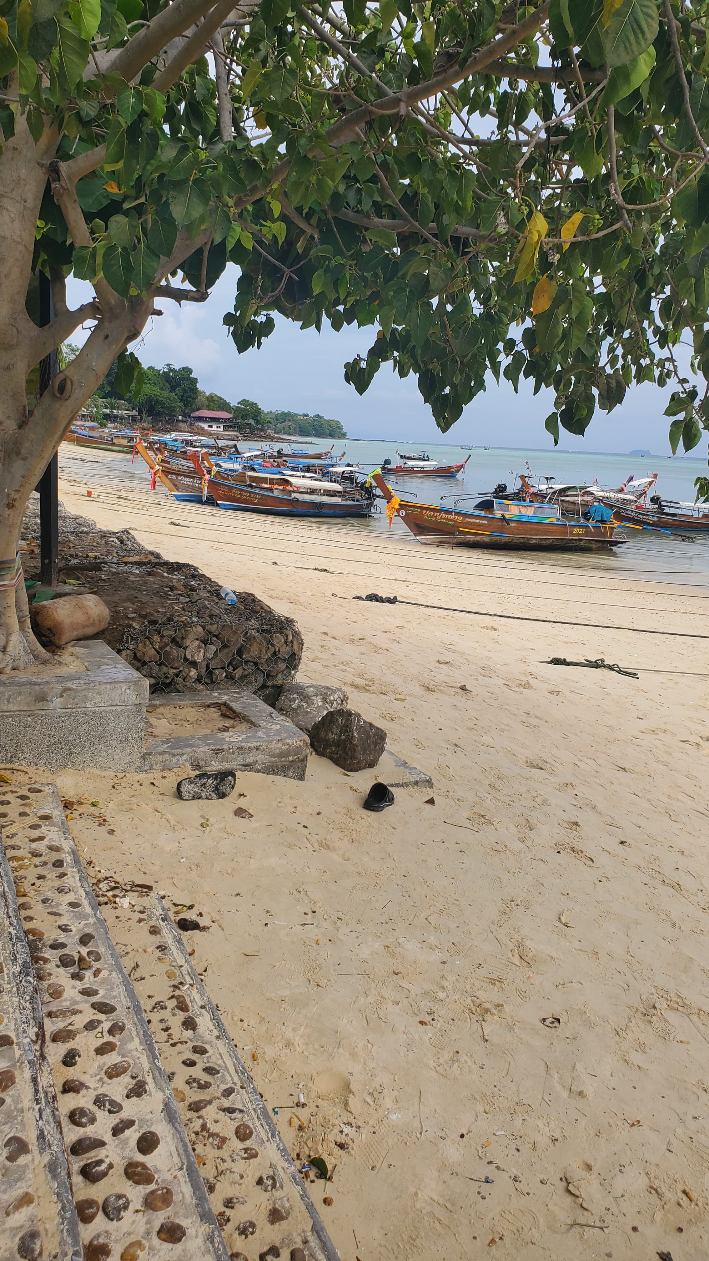 View of an empty white sand beach with several small fishing boats on shore