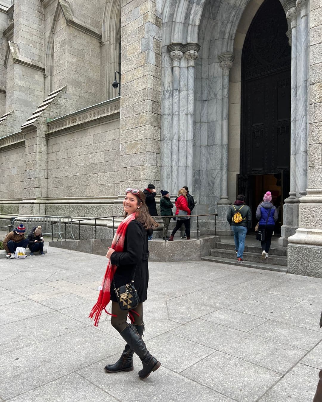 Advisor in a red scarf and black jacket in front of a large stone building