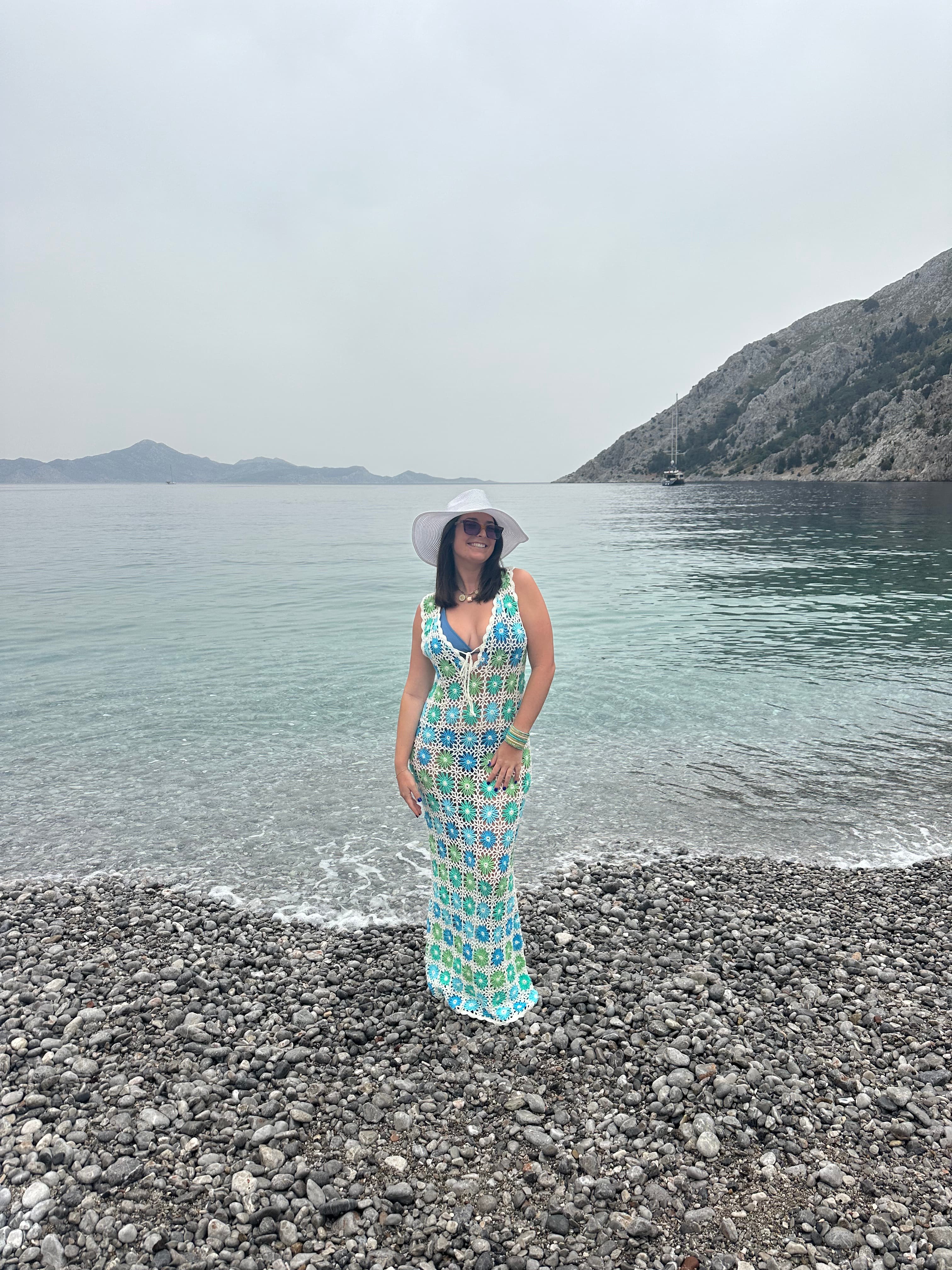 Advisor in a long dress posing on a rocky beach under cloudy skies