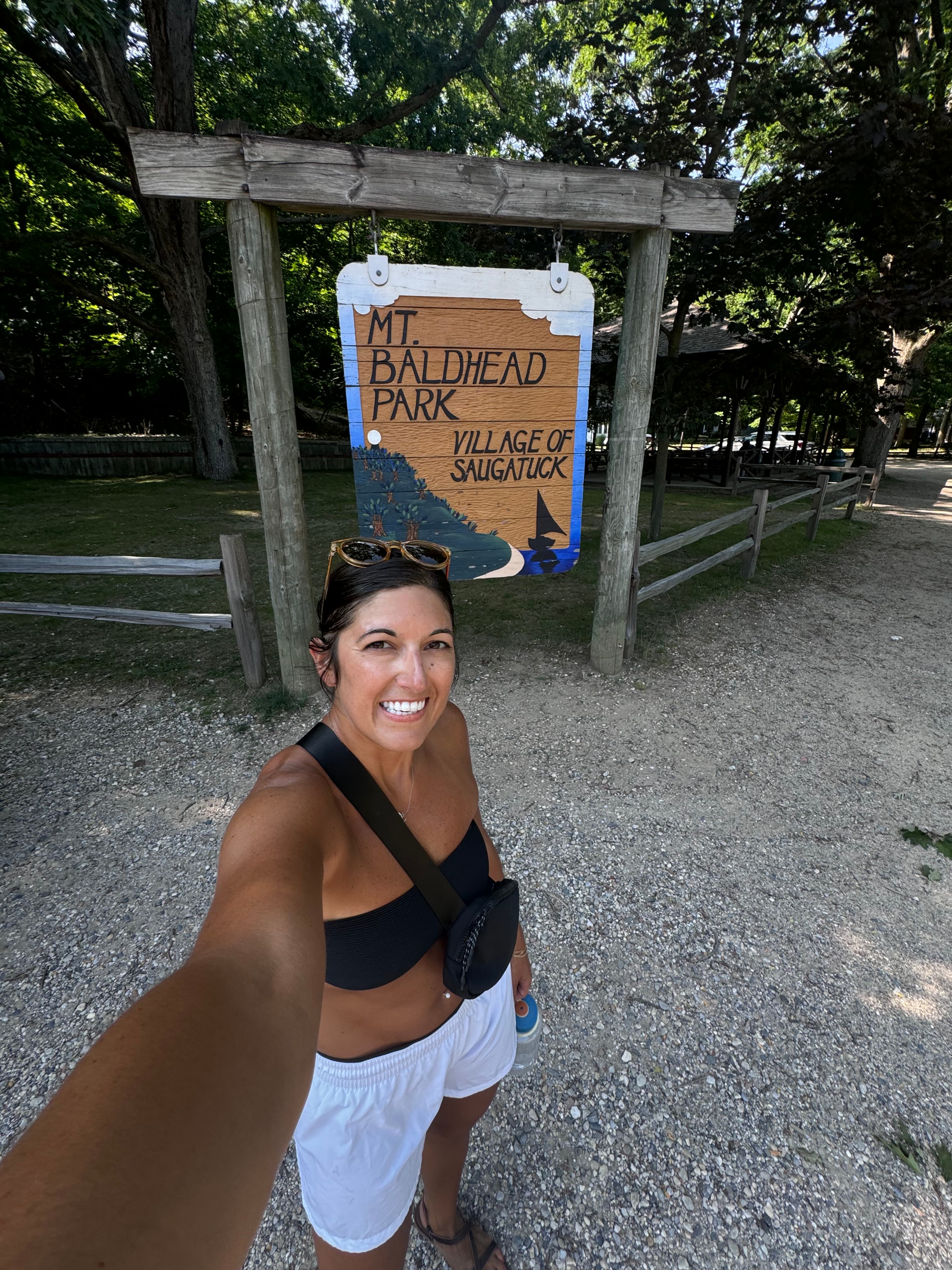 Advisor taking a selfie in front of a wooden sign at the entry to a park