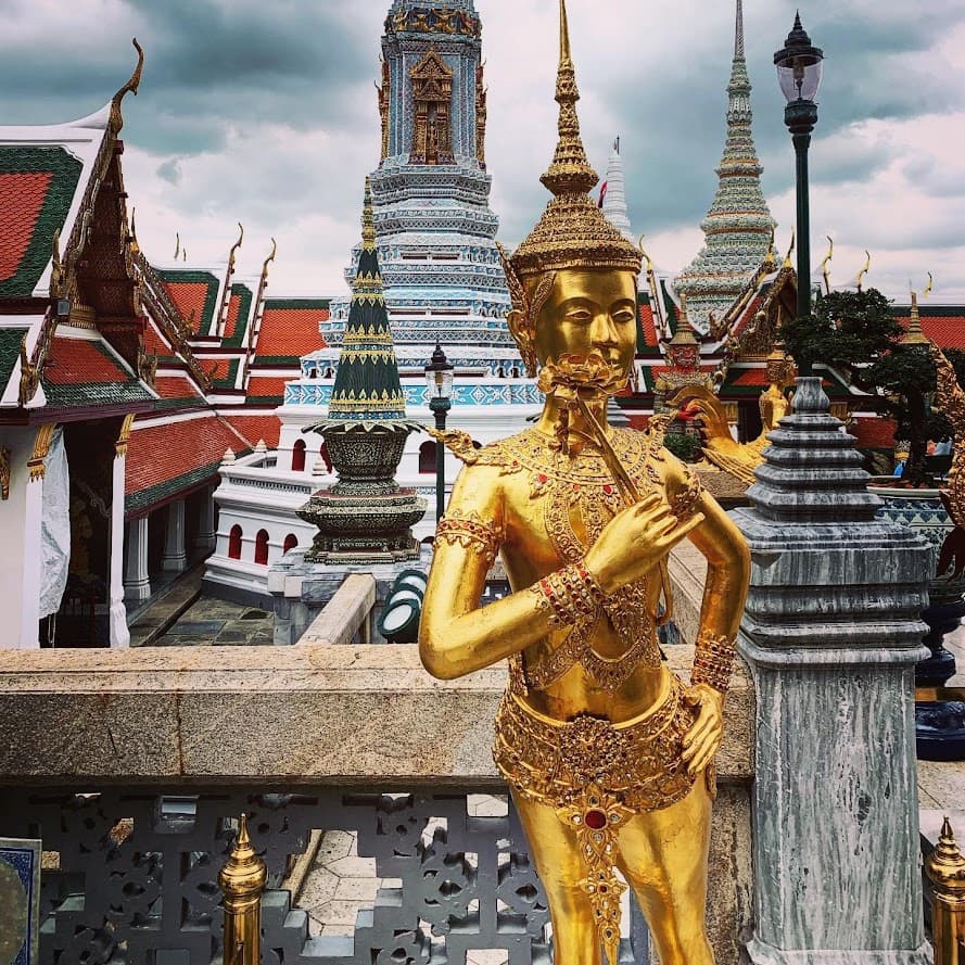  A golden statue of a Buddhist monk is prominently displayed in front of a temple.