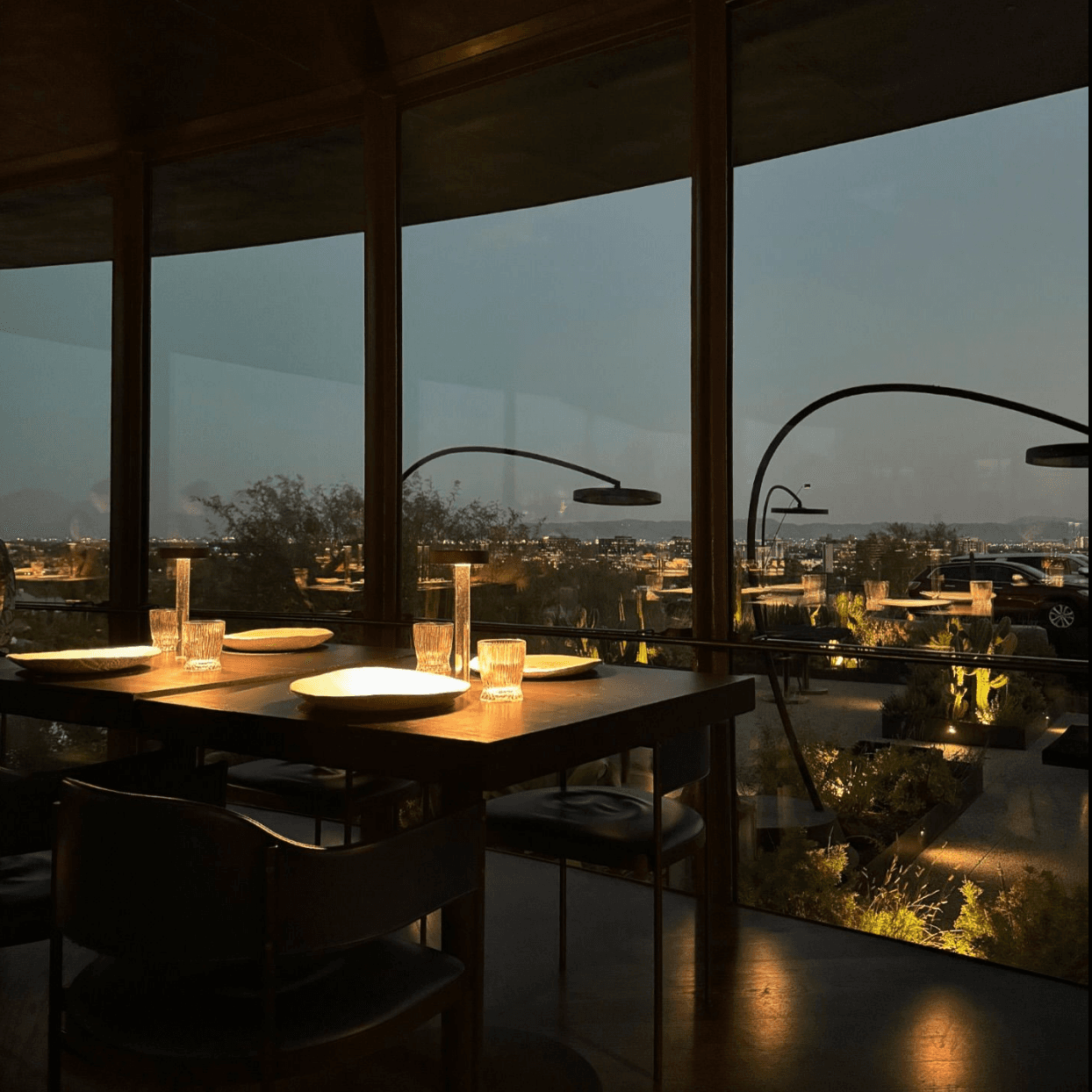 View of the interior of a dimly lit restaurant overlooking a cityscape at night