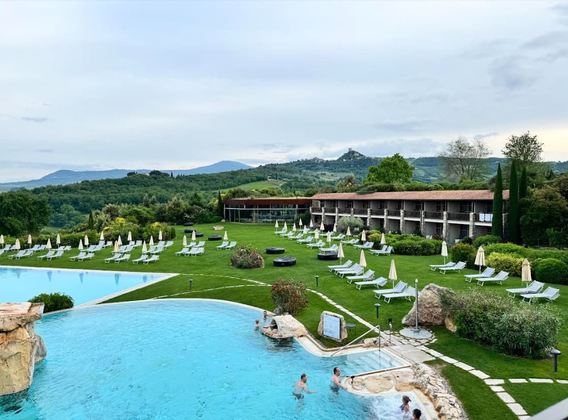 Aerial view of a resort pool surrounded by a grassy area with white lounges