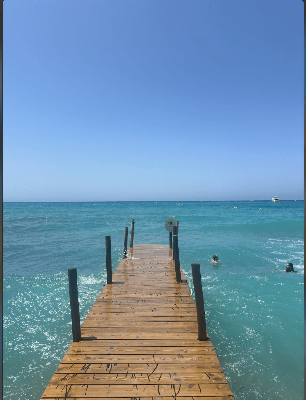 View of a narrow wooden dock stretching out to sea on a clear day