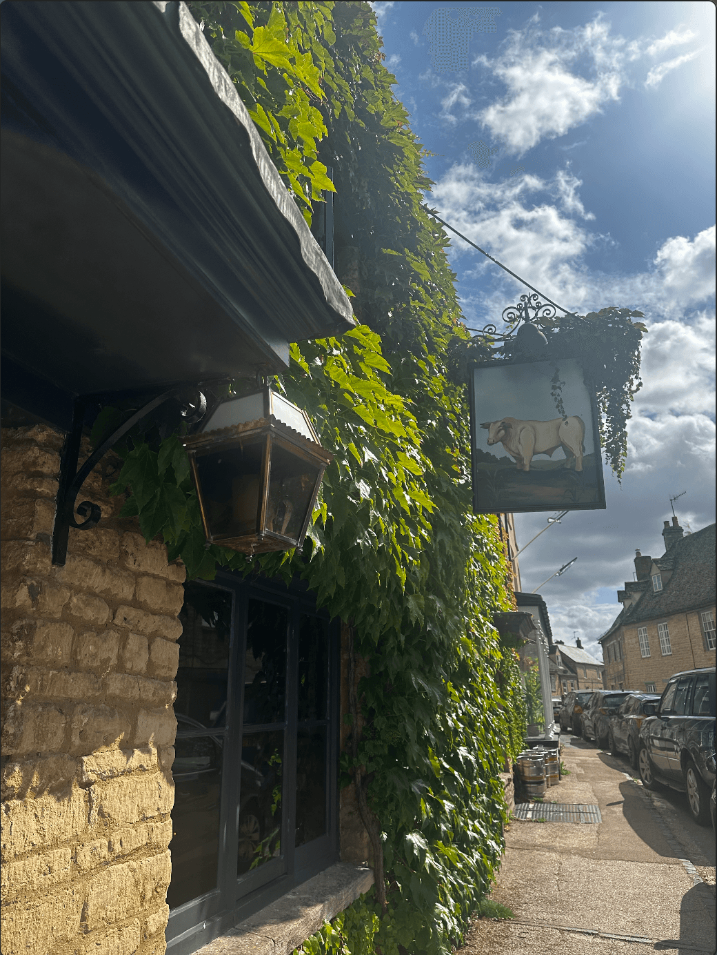 View of a hanging lamppost and sign in front of a brick building on a sunny day