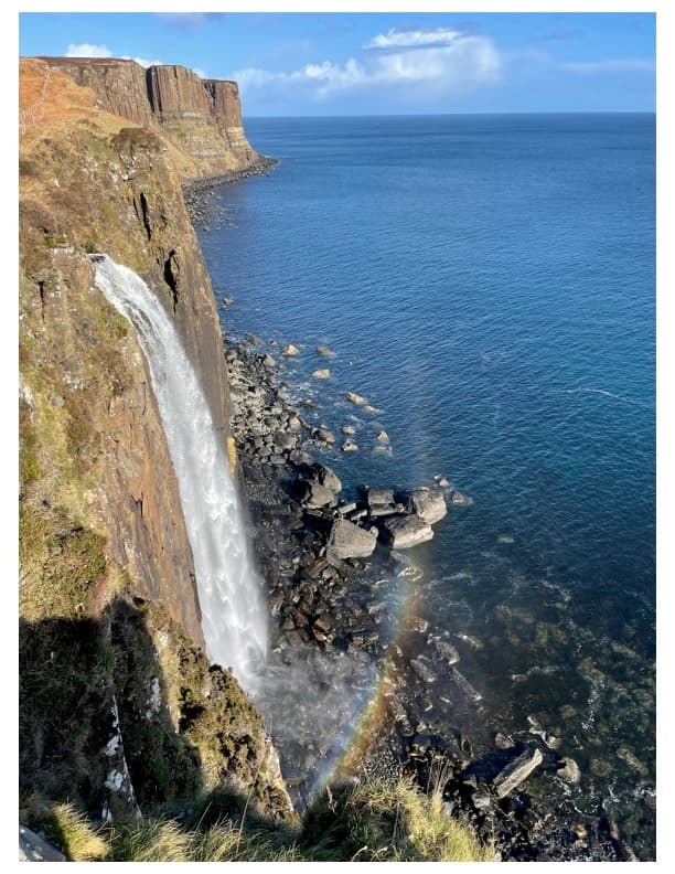 Beautiful view of a tall waterfall pouring into the sea on a sunny day