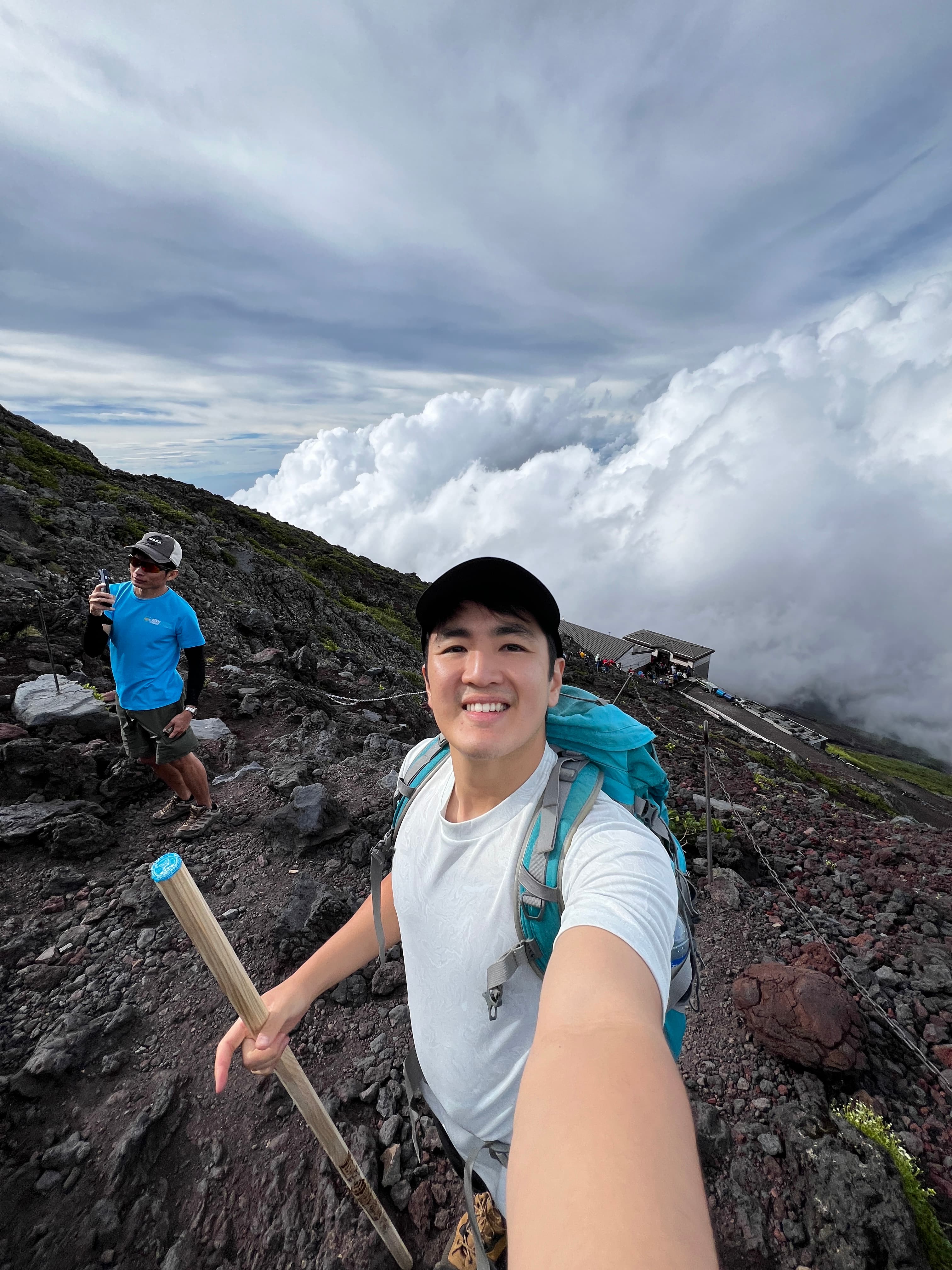 Advisor smiling and taking a selfie on the side of a rocky mountain high above the clouds