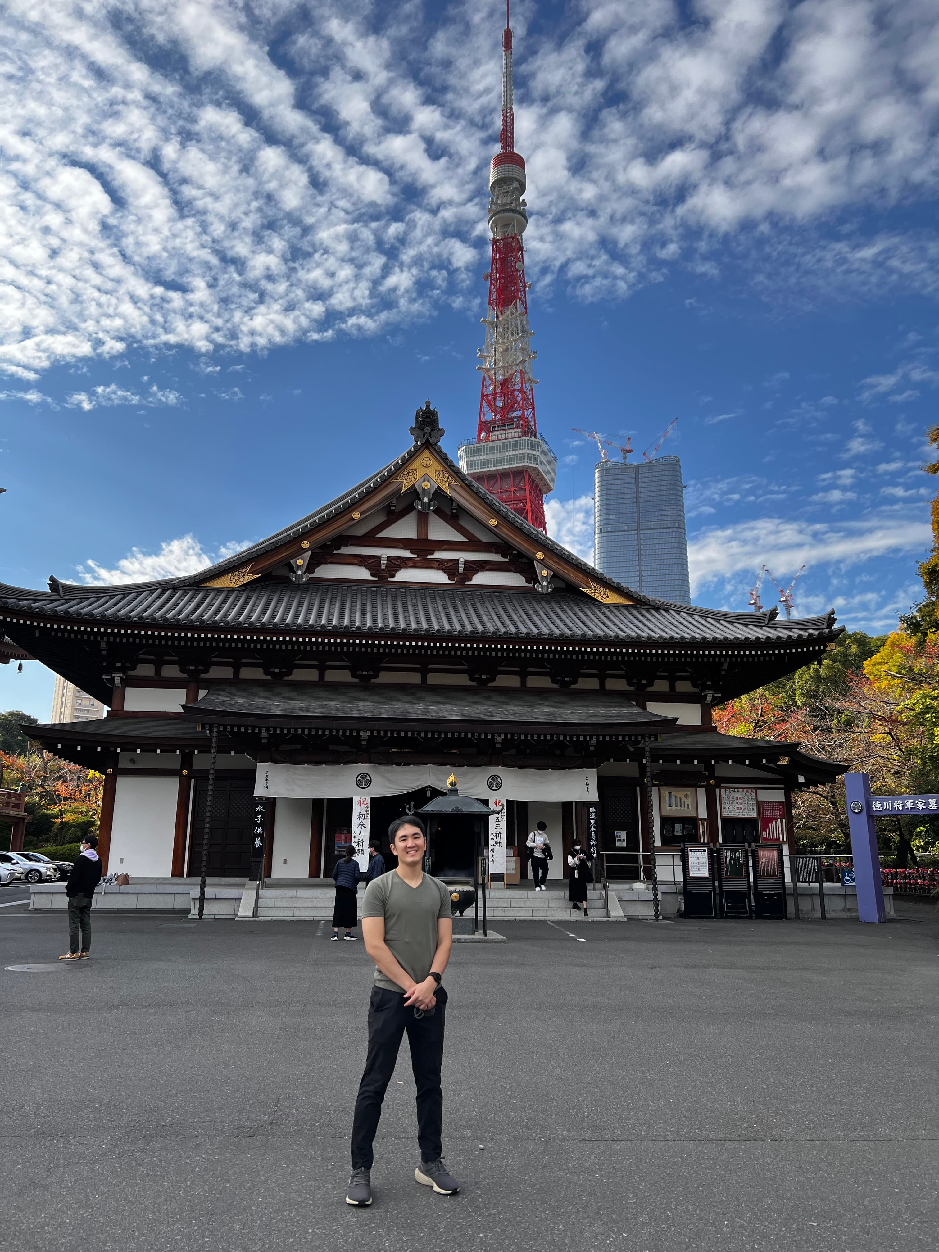 Advisor standing with hands clasped in front of a temple in Japan on a sunny day