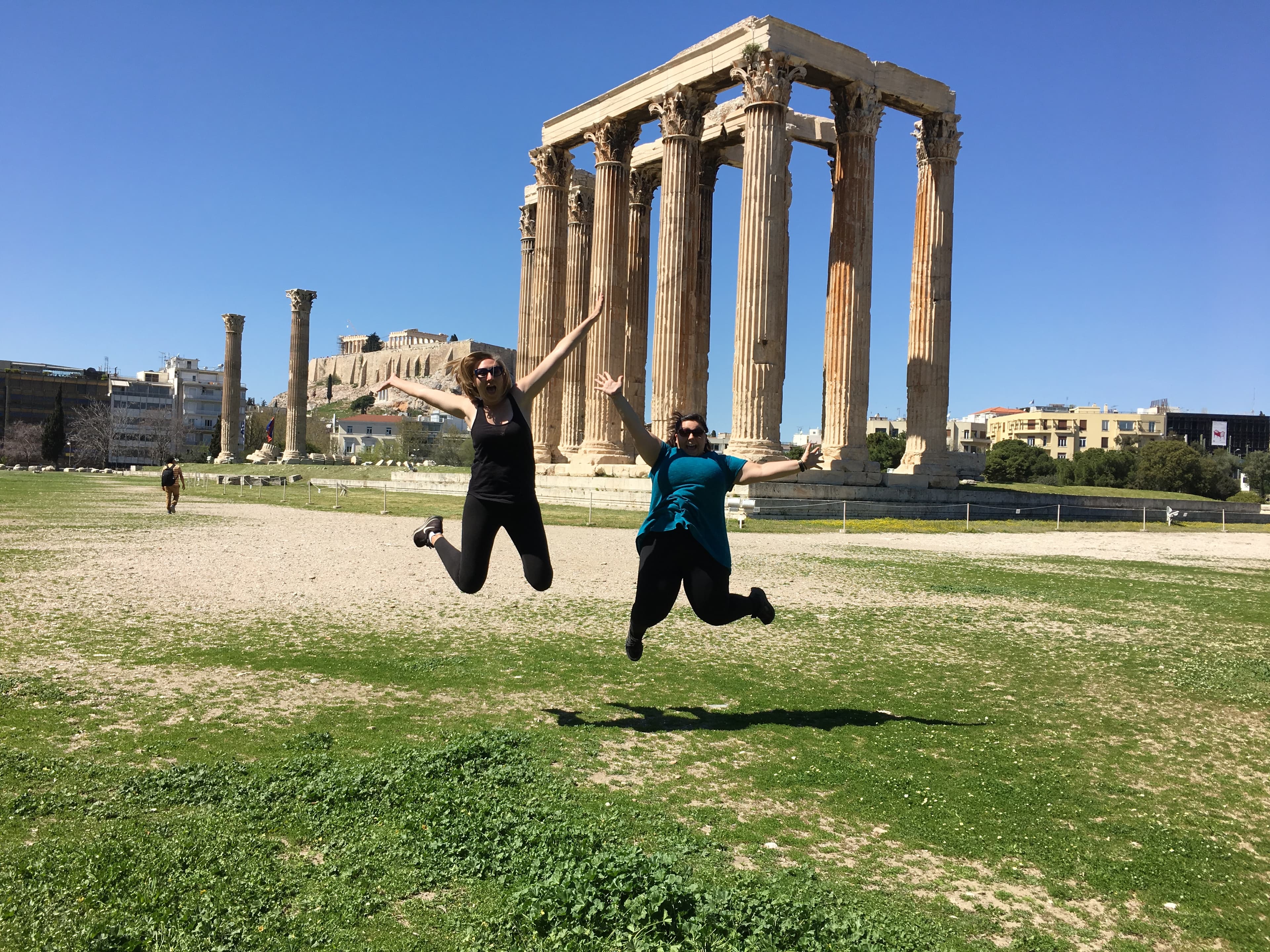 Advisor and friend jumping in front of ancient columns on a sunny day