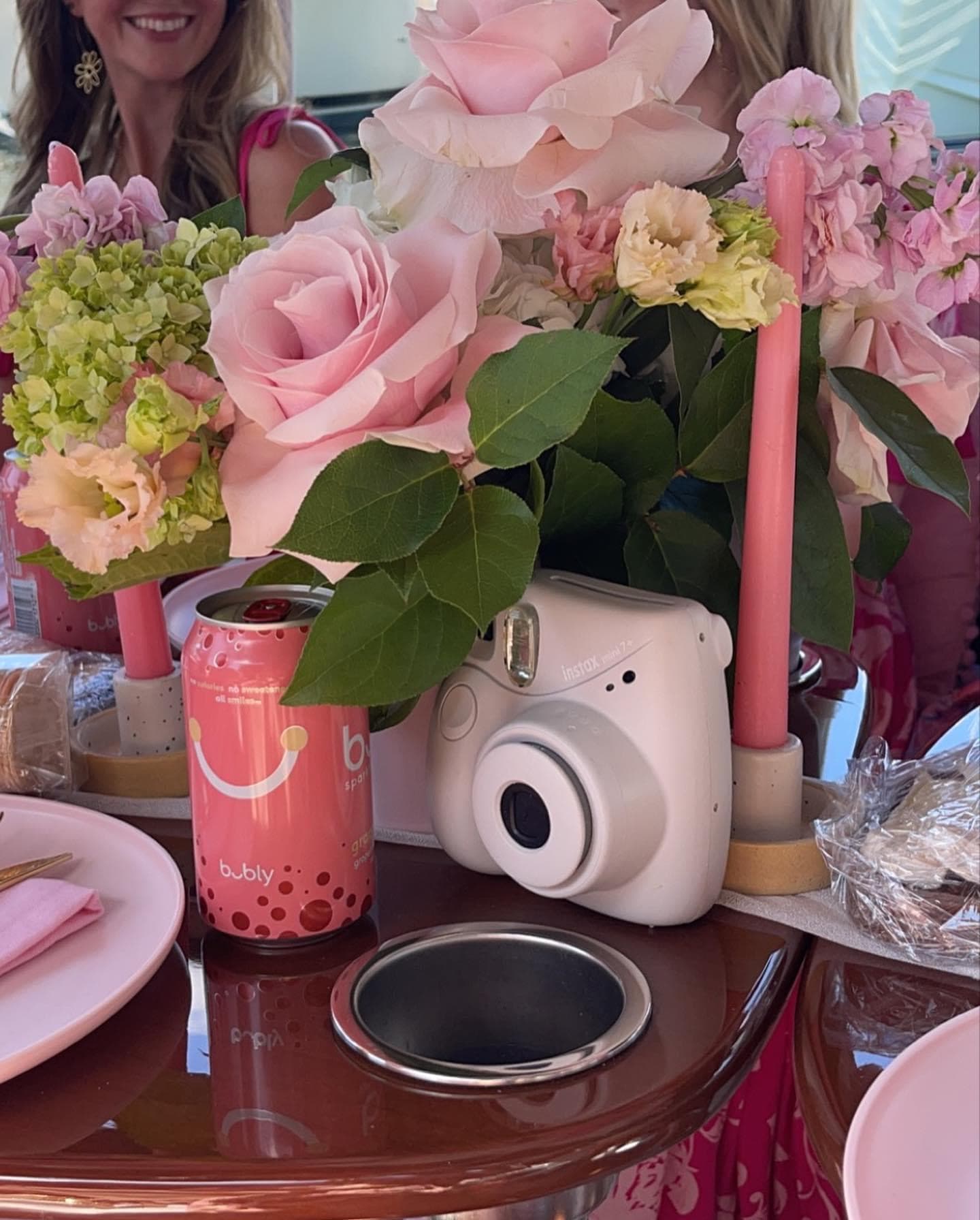 View of a table set with a pink bouquet, pink candles and a pink Polaroid camera