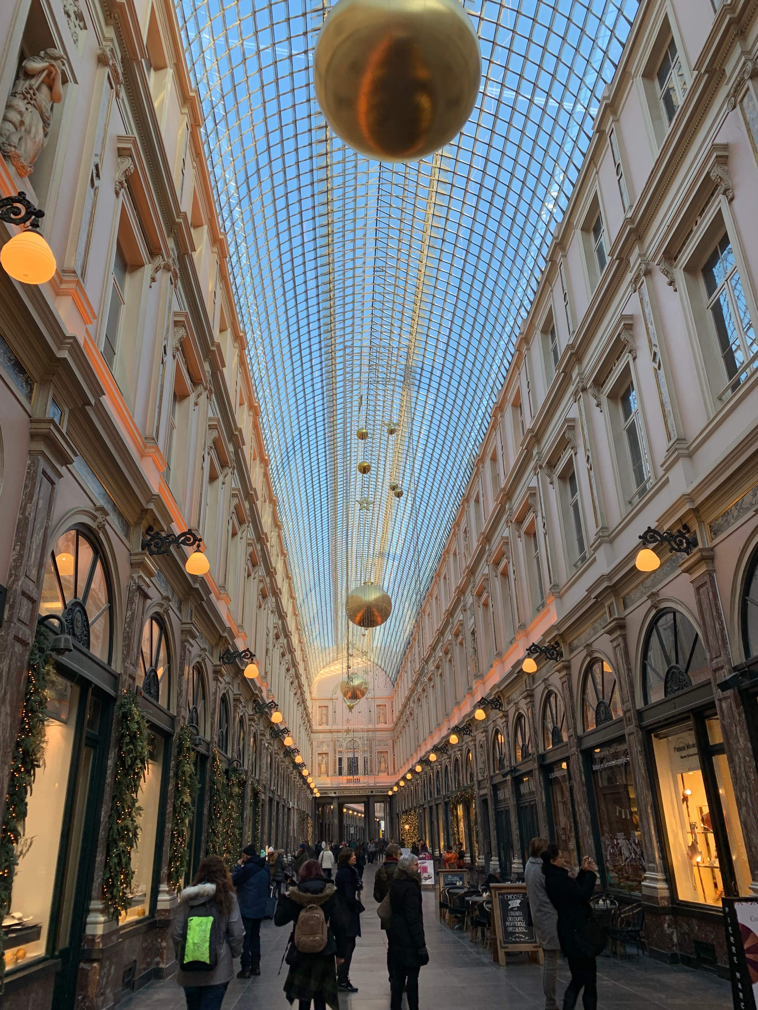 View of a long hall lined with shops and windows with hanging circular chandeliers above