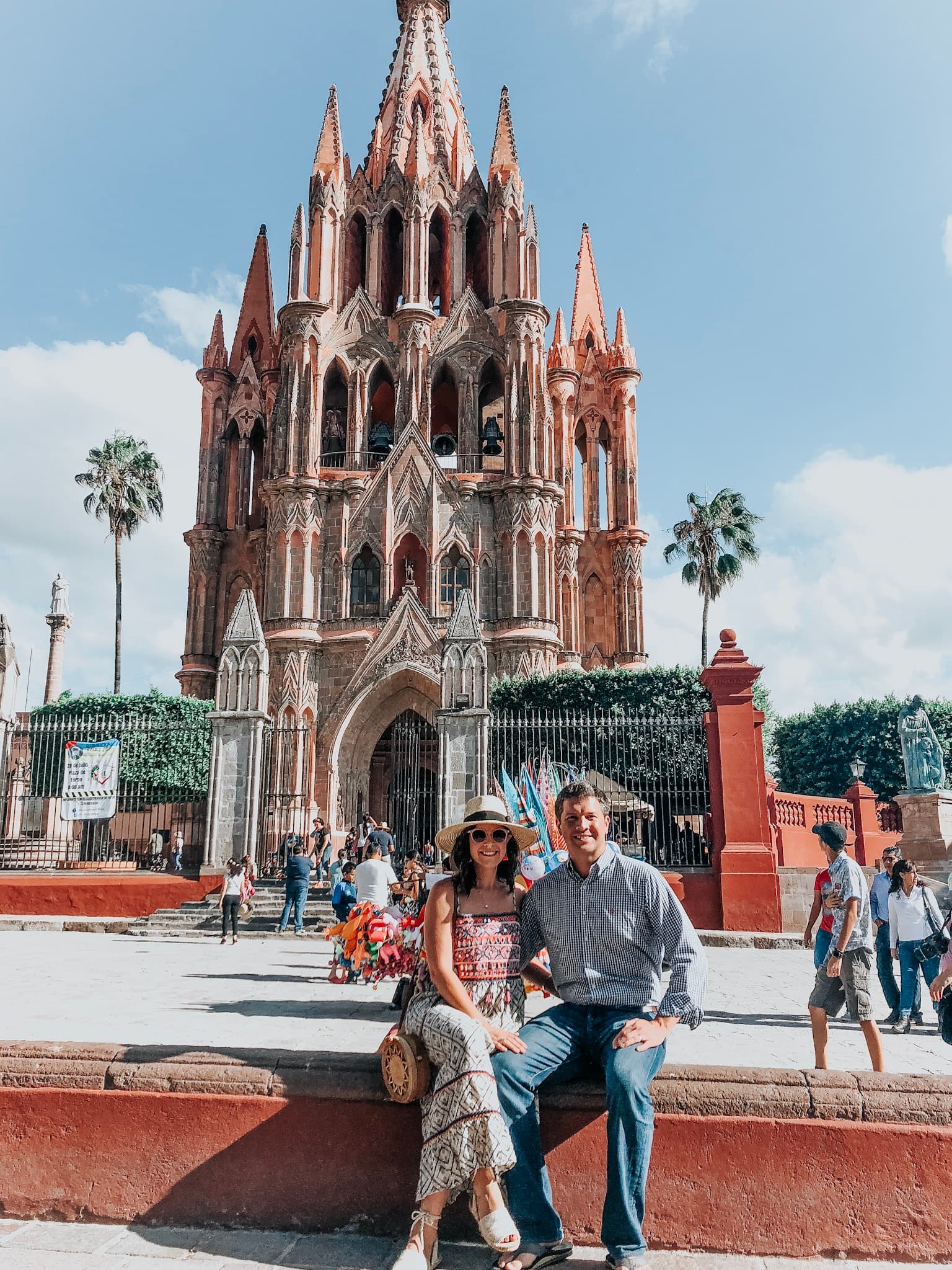 Advisor and partner sitting side by side on a sunny day in front of the pink cathedral in San Miguel de Allende, Mexico