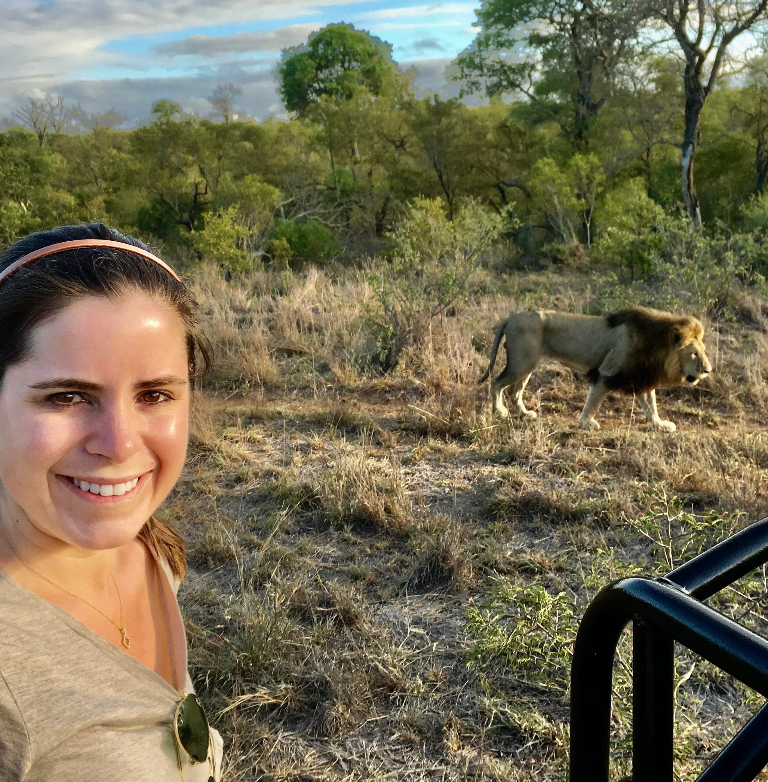 Advisor taking a selfie on a safari with a lion visible behind her