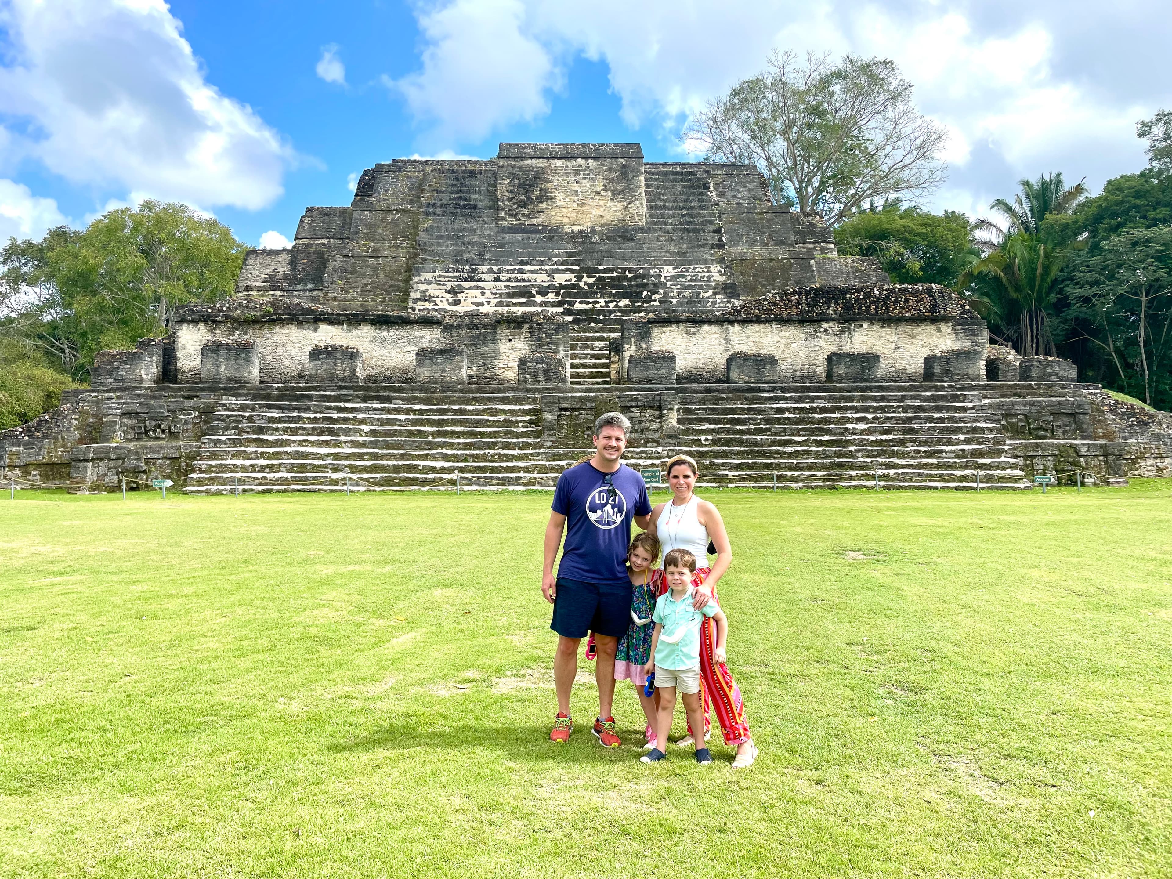 Advisor and family posing together on a grassy lawn in front of an ancient stone pyramid