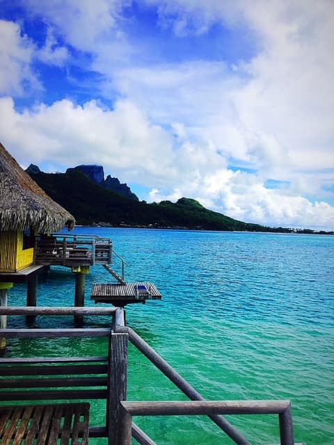 View of a turquoise sea as seen from a wooden overwater bungalow on a sunny day