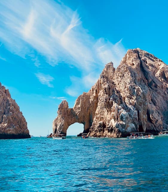 View of a rock formation with archway out at sea on a sunny day