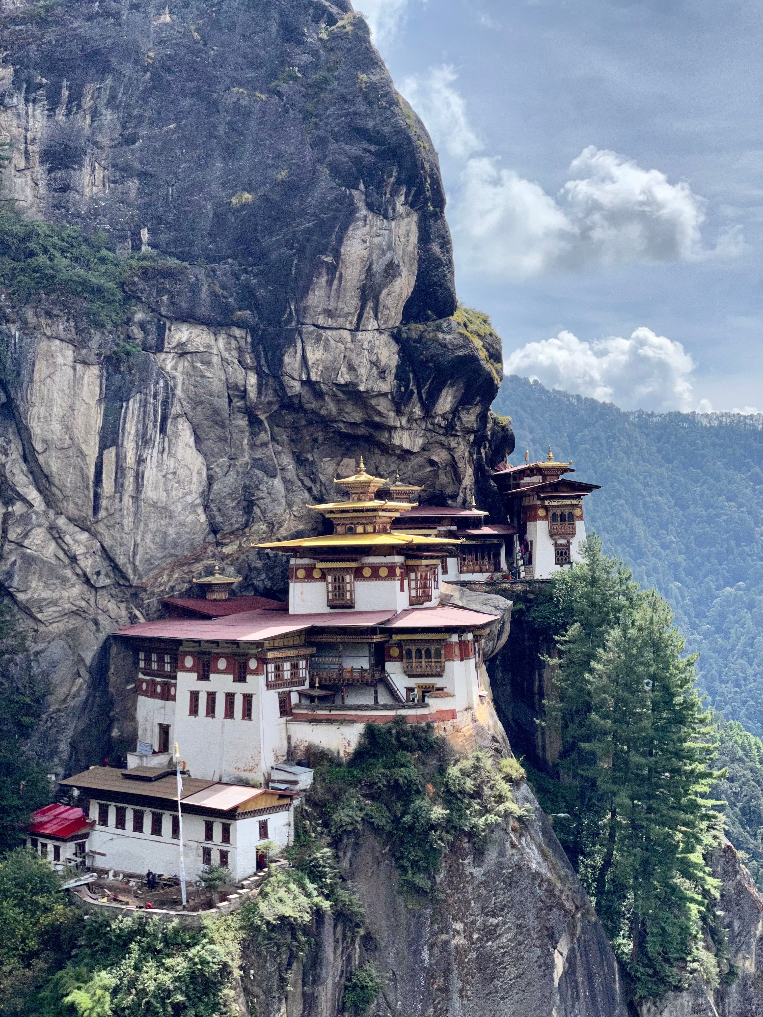 A view of a temple on a mountain side with beautiful ascending cliffs. 