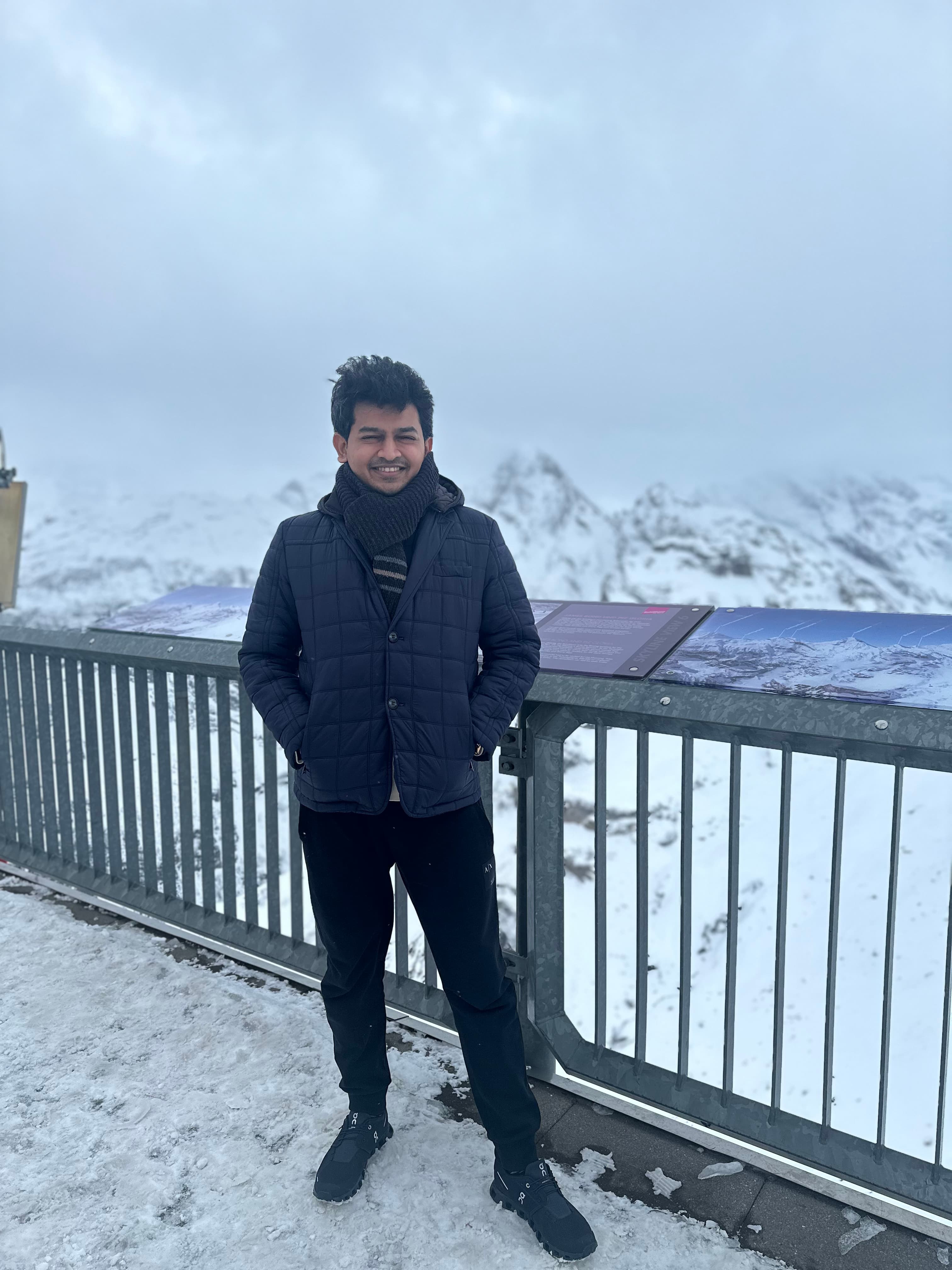 Advisor in winter clothing standing outdoors on a rooftop overlooking snowy mountains on a cloudy day