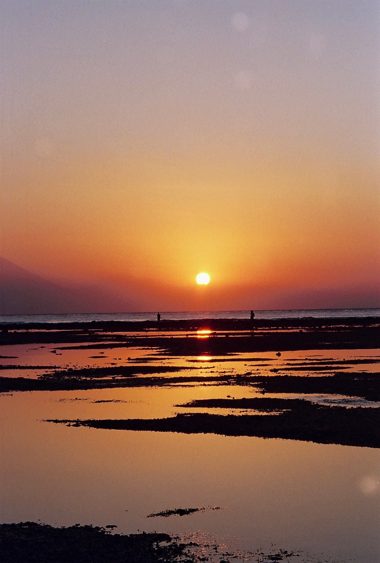 View of an orange sunset over flat wetlands