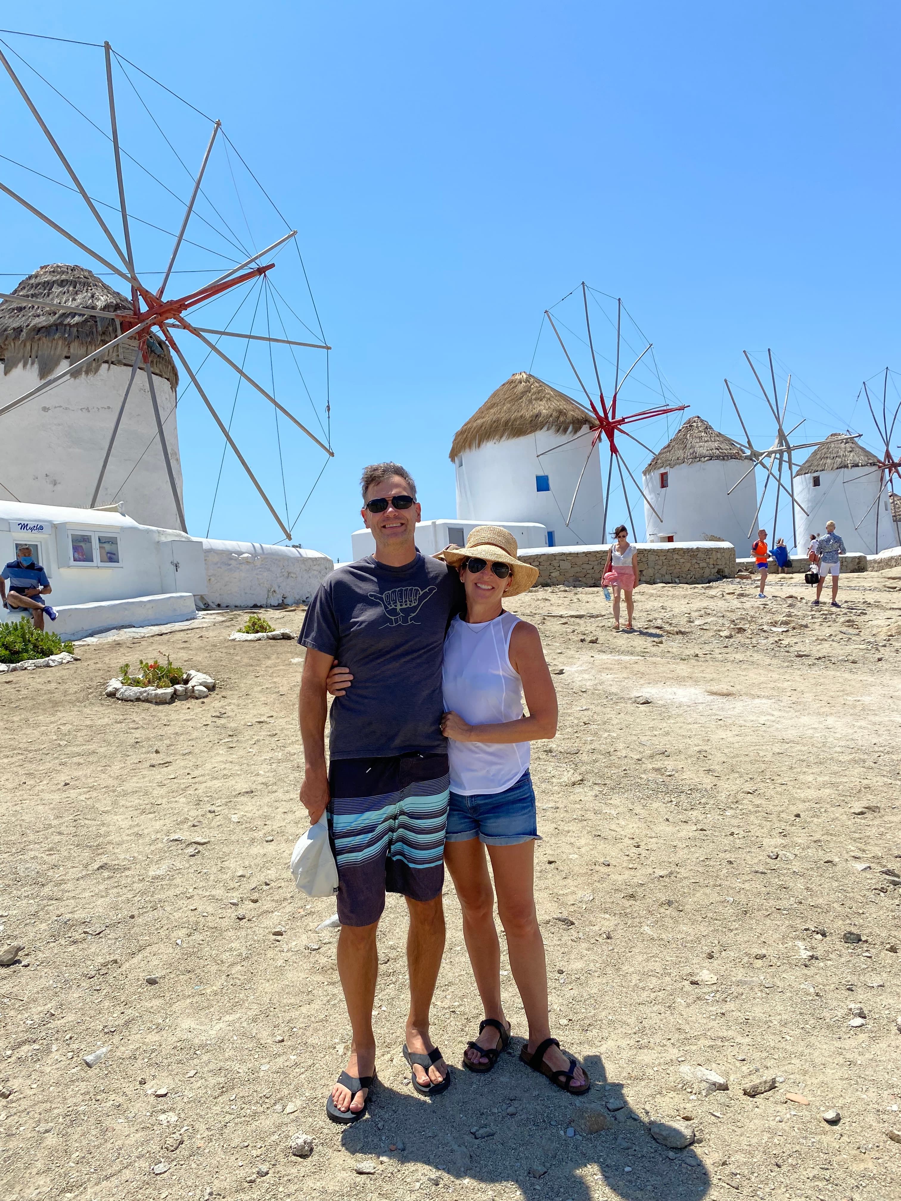 Advisor and partner standing side by side with old white windmills in a line behind them