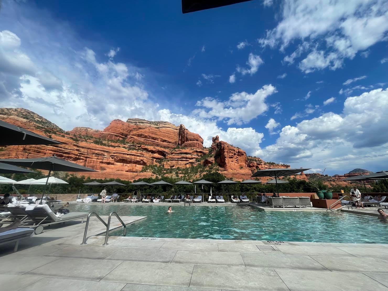 View of a sunny resort pool with beautiful red rock formations rising in the background