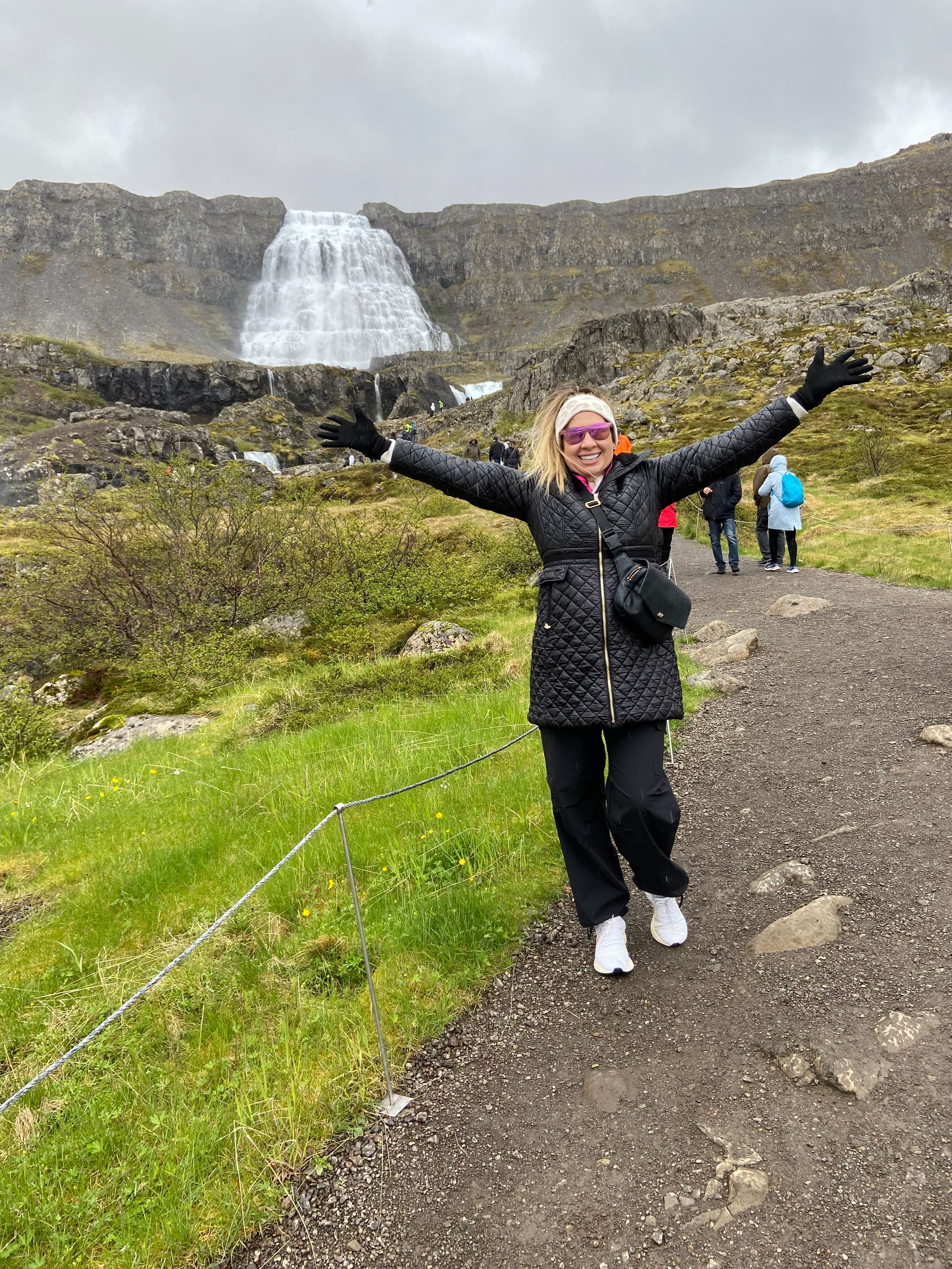 Advisor posing with arms raised with a massive waterfall visible in the background