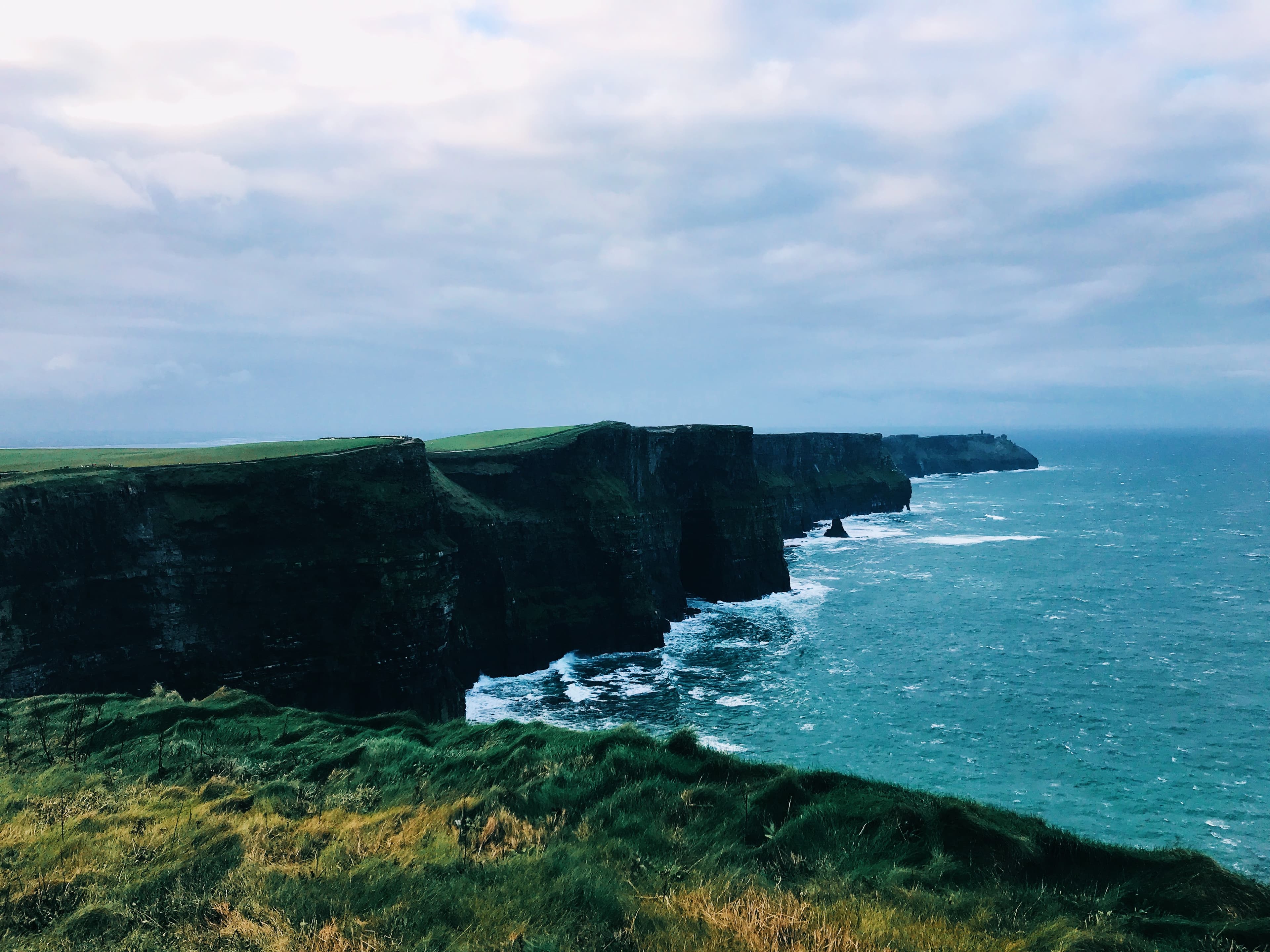 A view of the ocean with large cliffs in the distance on a sunny day.